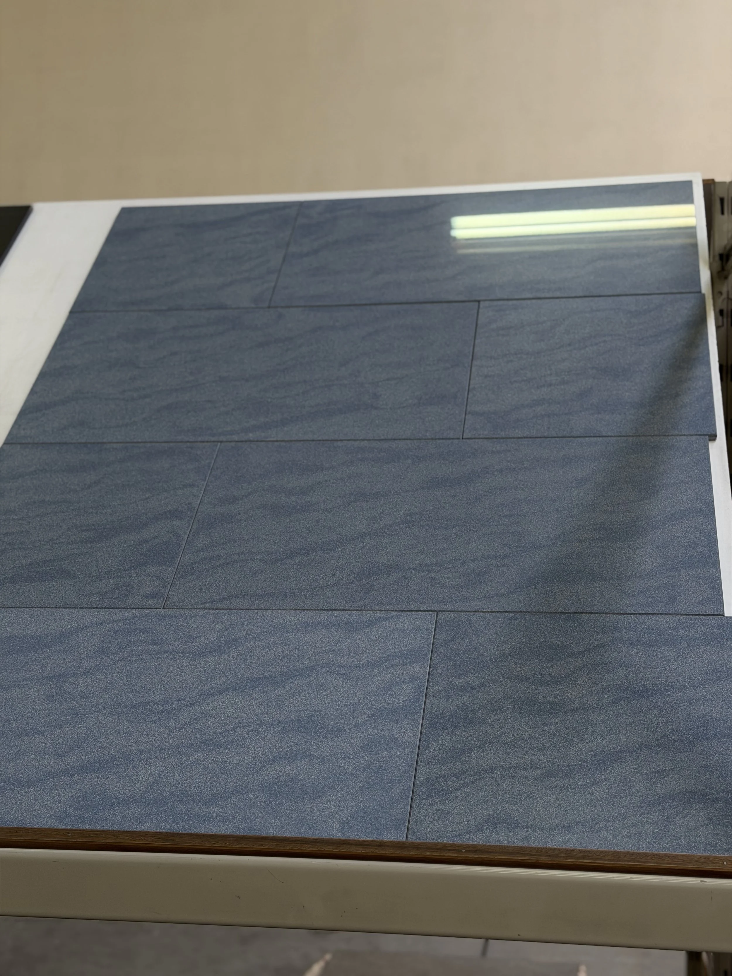 Een tafel met blauwe vloermatten en een witte rand, in een kamer met beige muur.