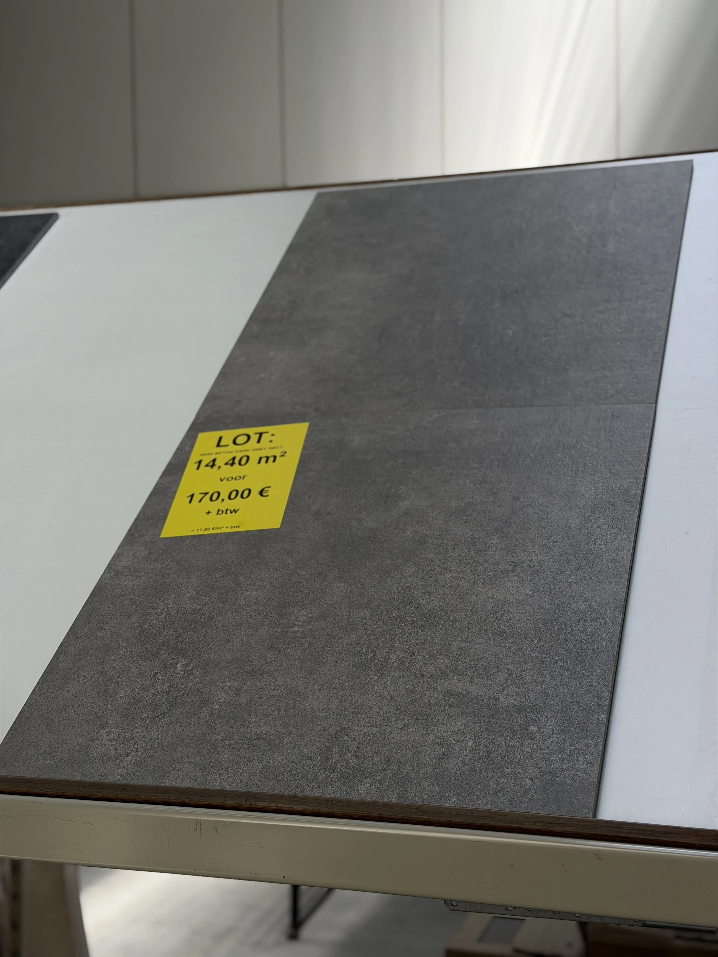 Een stuk vloerbedekking met een geel prijskaartje dat aantoont dat het 14,40 vierkante meter kost voor €170,00 inclusief BTW.