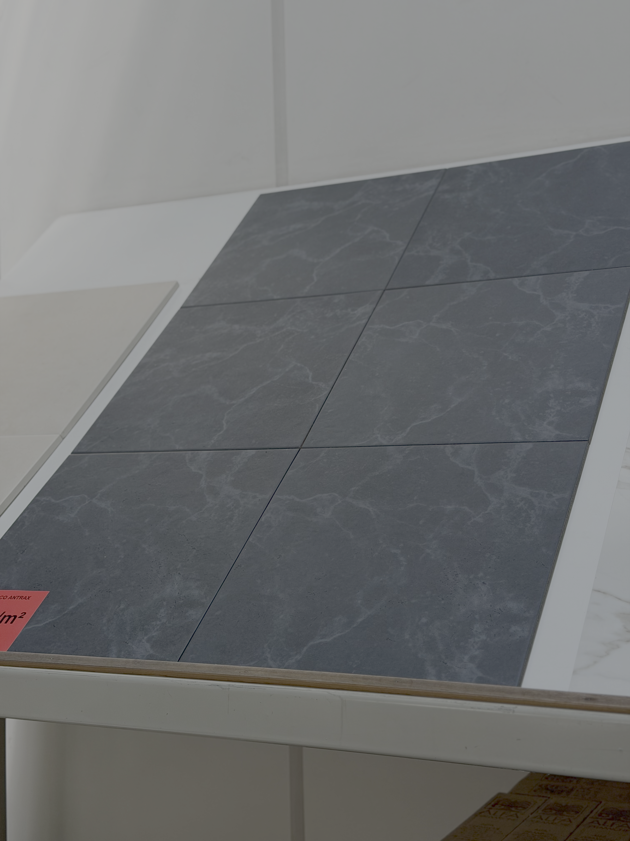 Tegels van donkergrijze marmer op een witte tafel in een winkel of showroom.