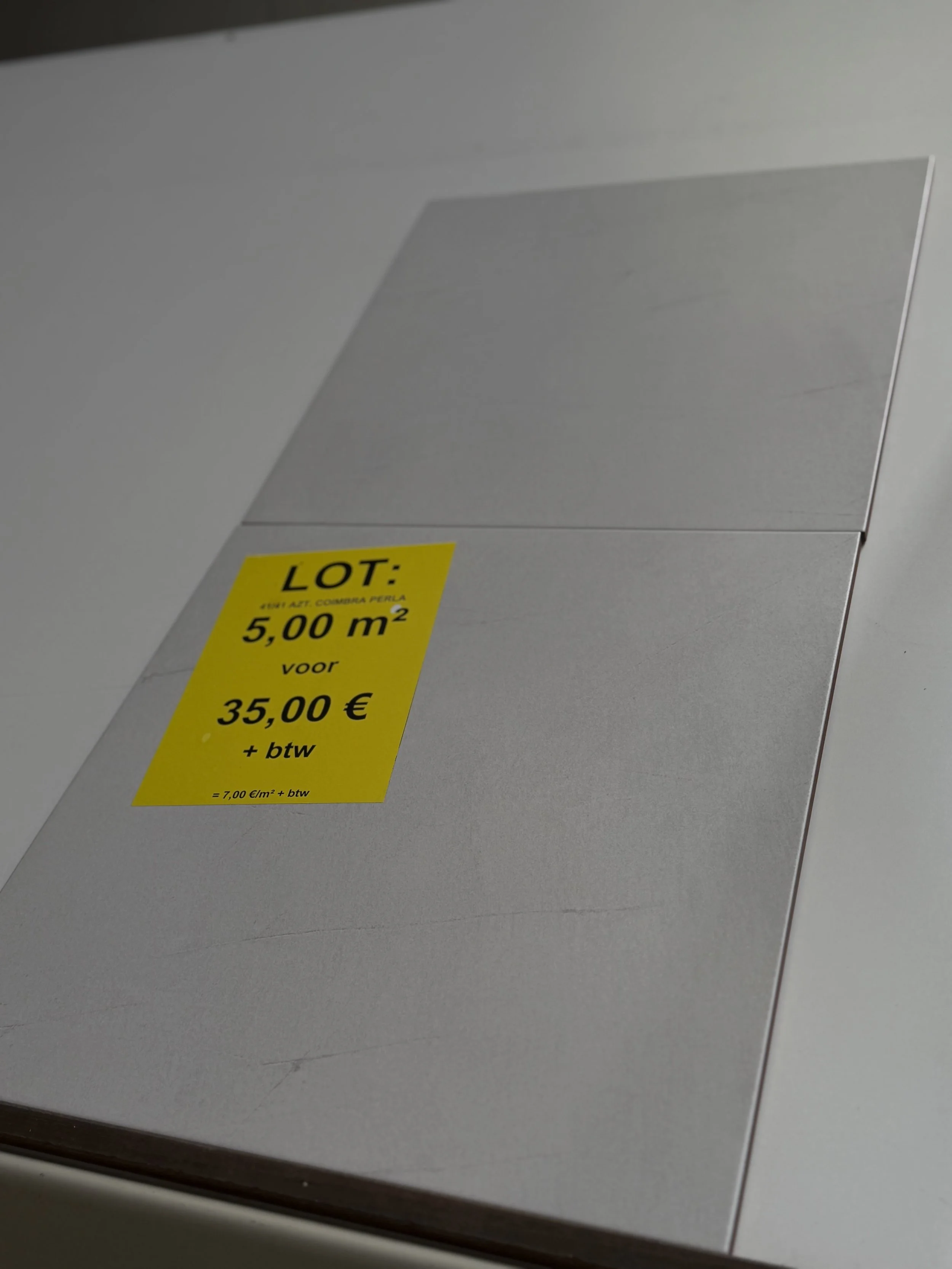 Gele sticker op een witte doos met informatie over een lot van 5.00 m² voor 35,00 euro plus btw, en een prijscalculatie op de onderkant.