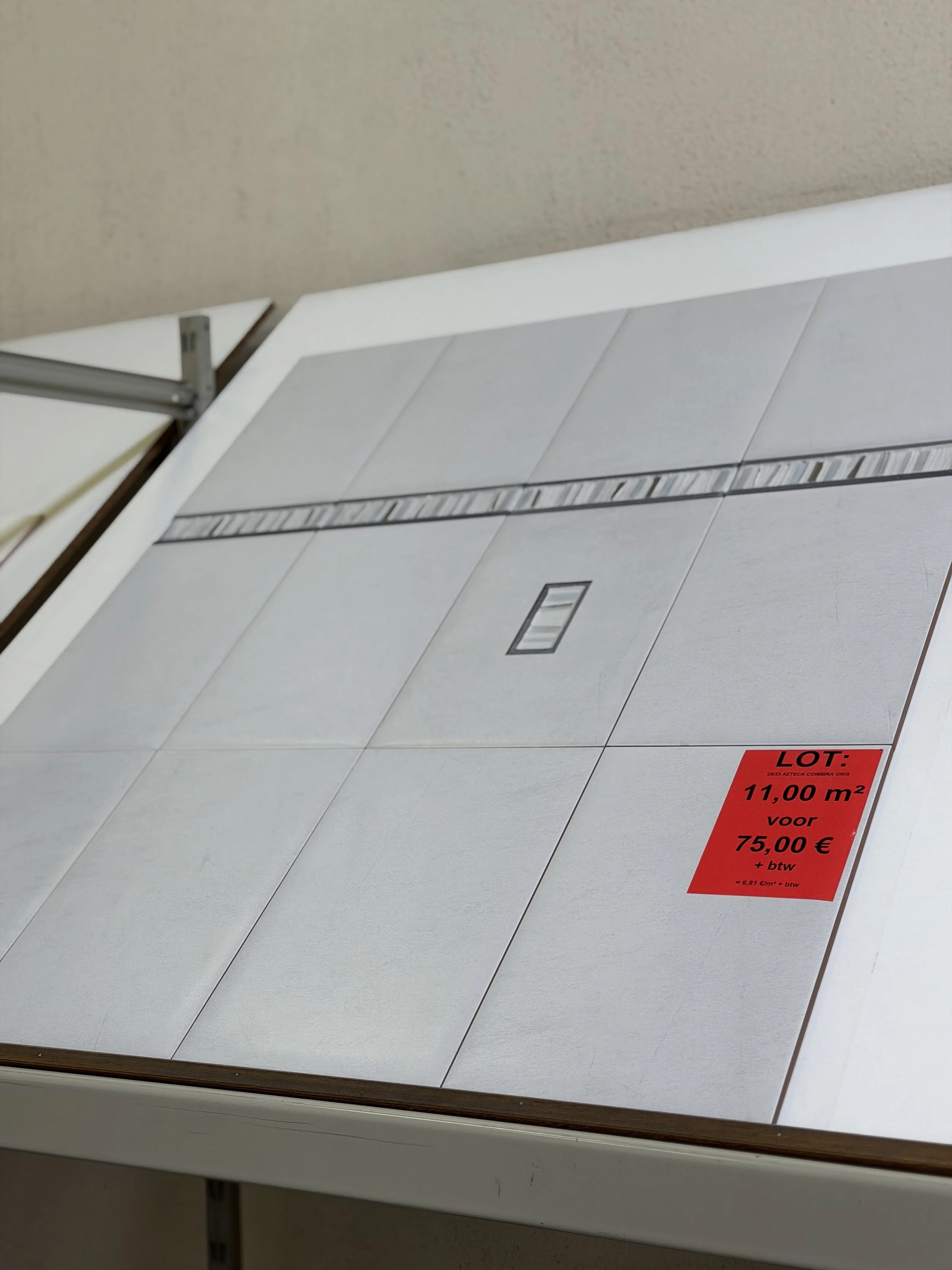 Tegels gereed voor verkoop met een rode prijsetiket dat een oppervlakte van 11 m² aangeeft, te koop voor 75 euro plus btw.