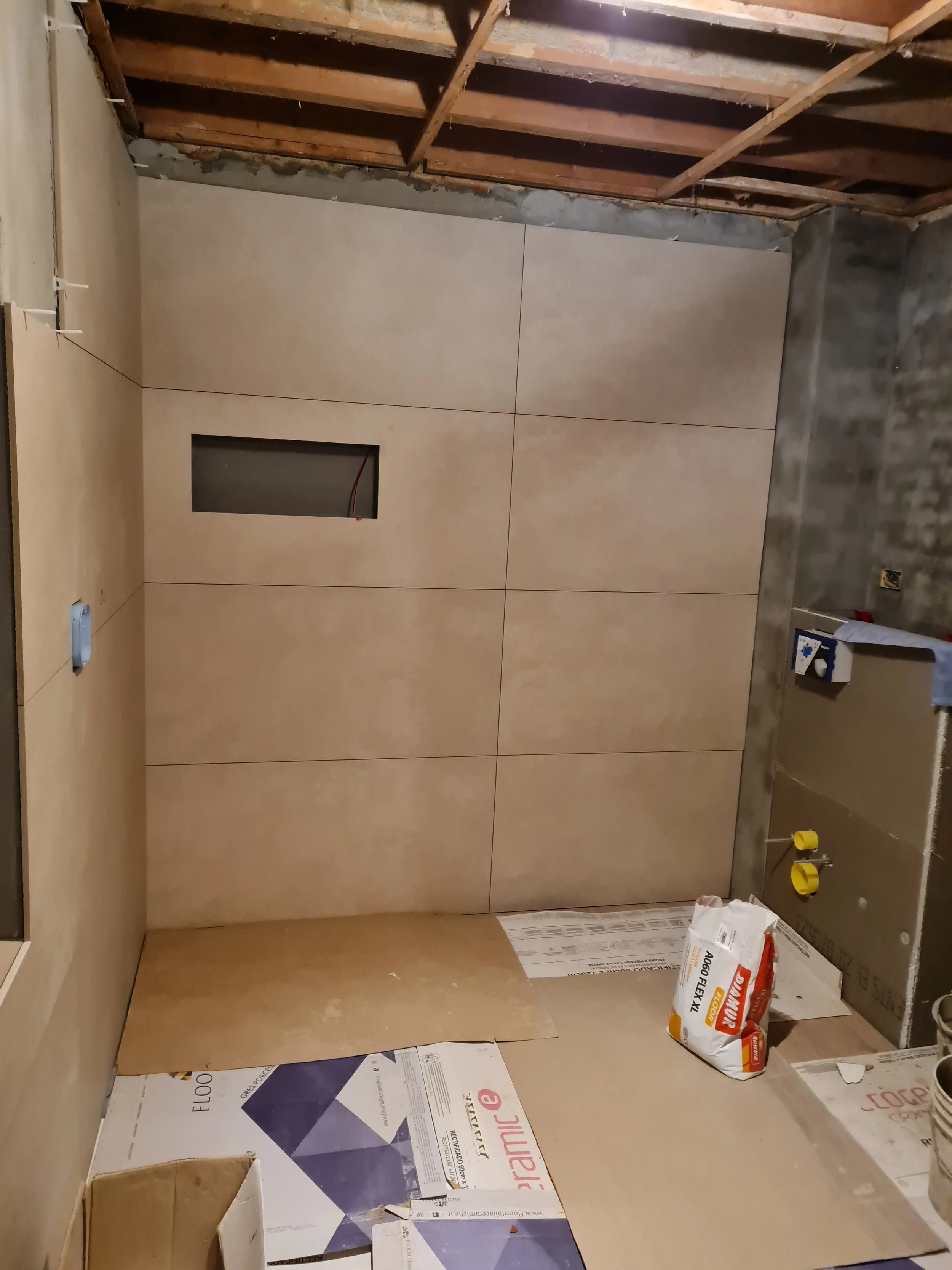 Binnenkant van een kamer met onvoltooide muurafwerking en bouwmaterialen zoals isolatie en gipsplaten, klaar voor verdere afwerking.