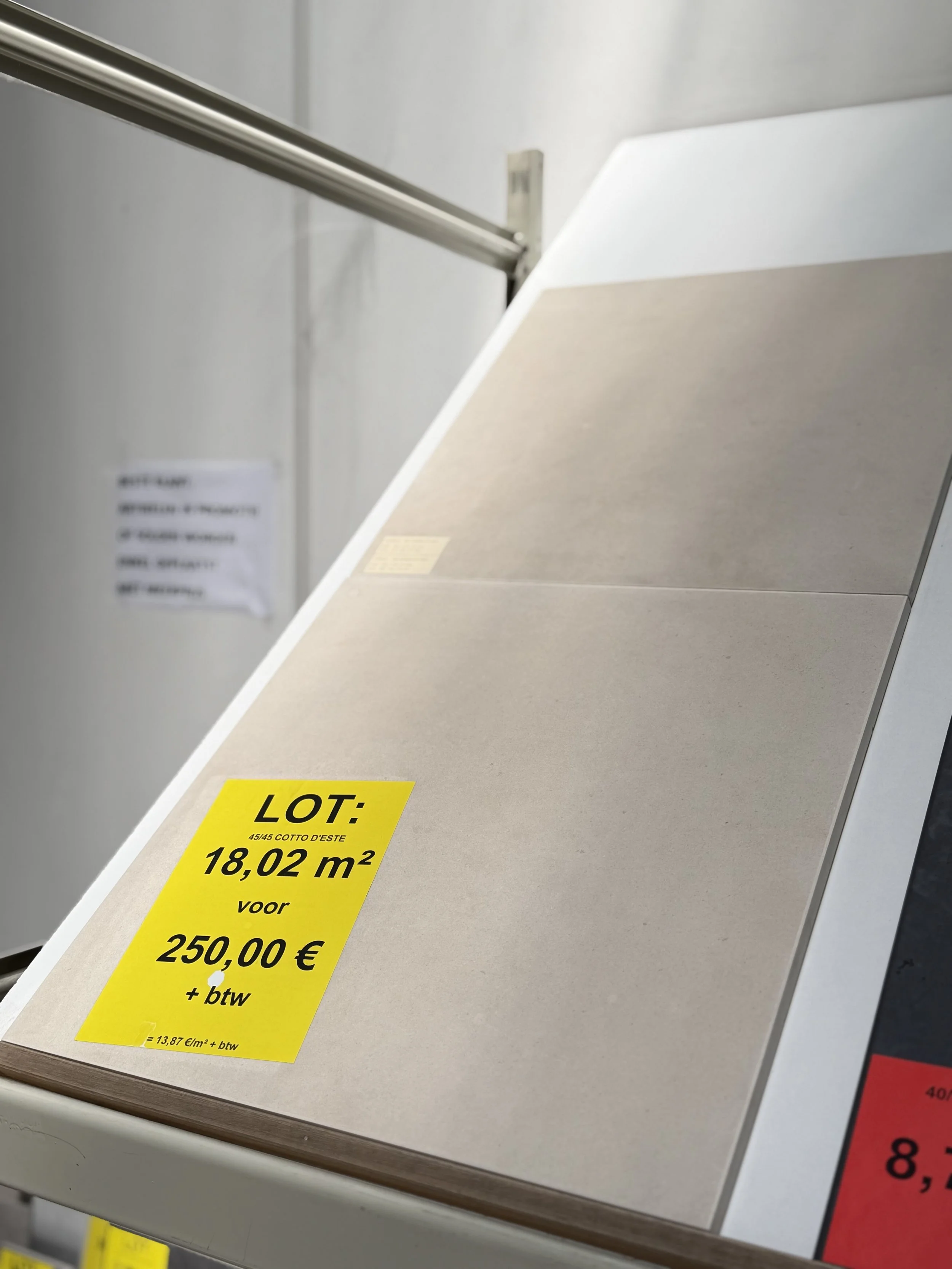 Een close-up van een gele verkoopmarkering op een tafel, met informatie over een lot met een oppervlakte van 18,02 vierkante meter en een prijs van 250 euro plus btw.