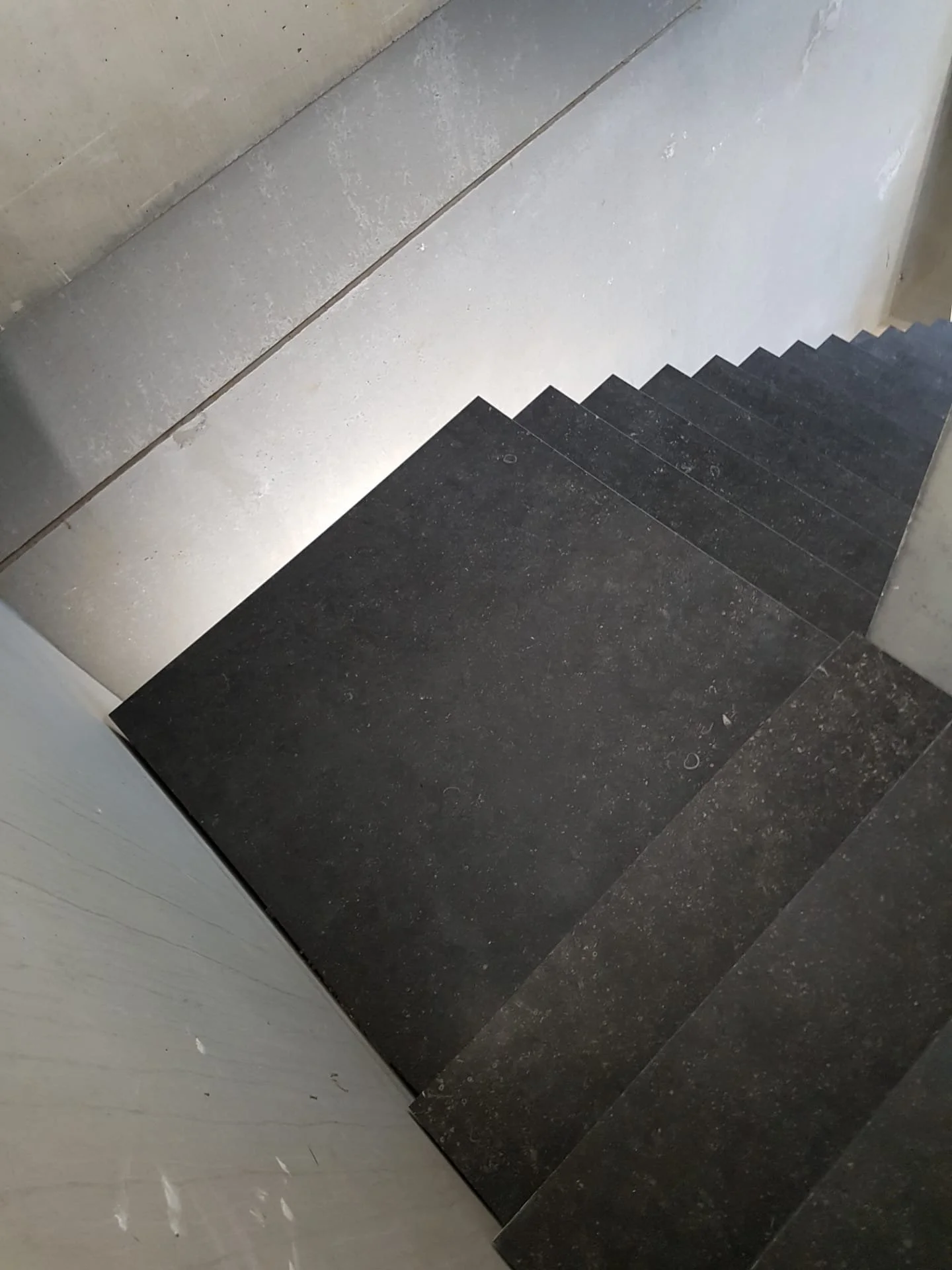 Een trap met zwarte treden en een witte muur aan de zijkant.