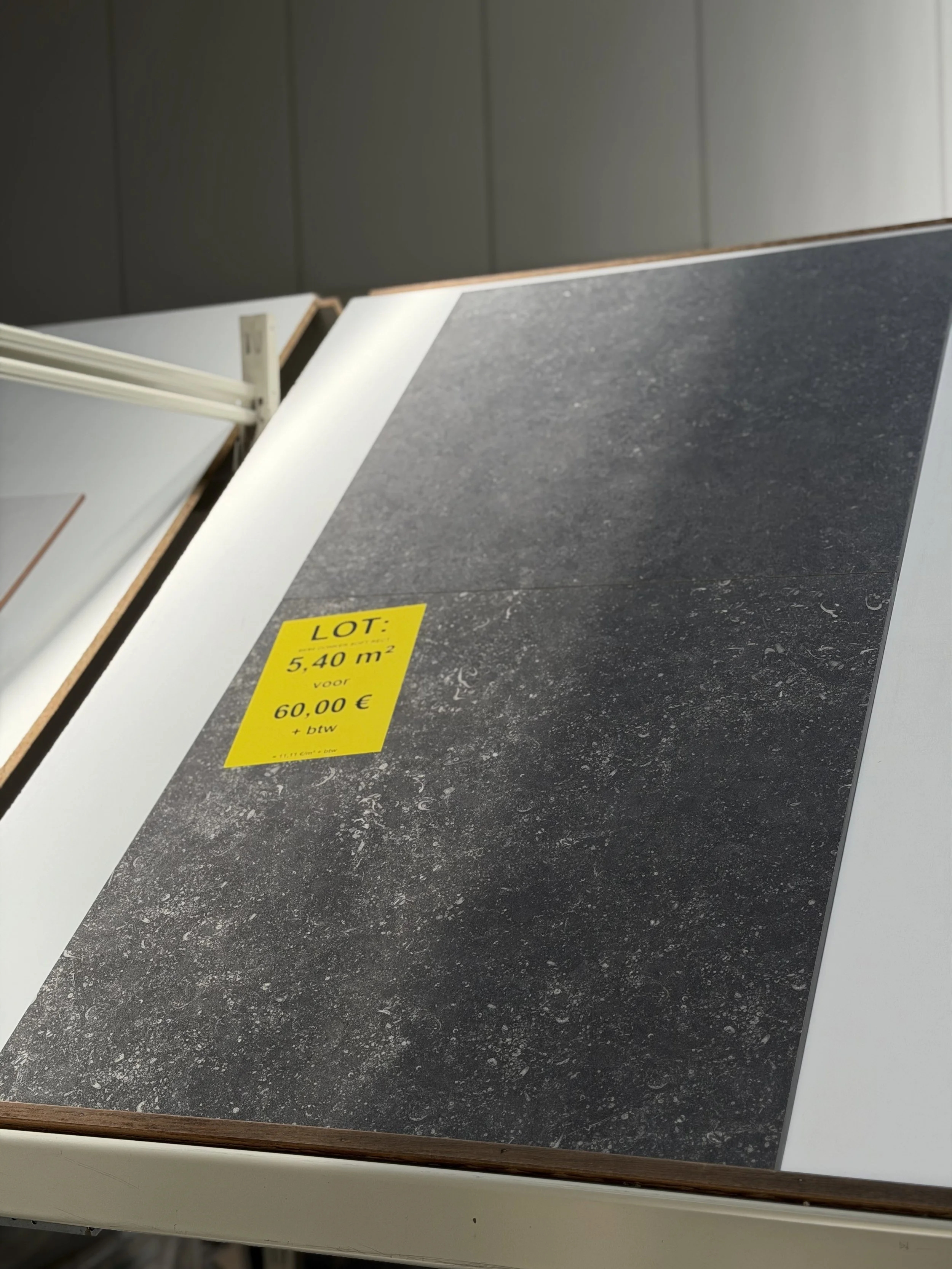 Een waterdichte vloer in een winkel met een gele verkoopkaart die aangeeft dat het vloeroppervlak 5,40 m² is en voor 60 euro plus btw wordt verkocht.