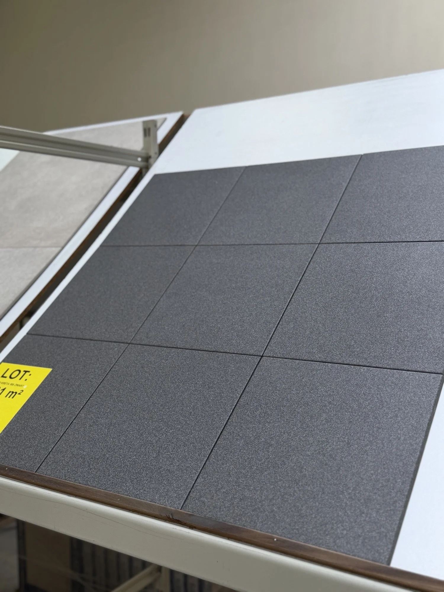 Steenplaten in verschillende kleuren en texturen liggen op een tafel, met een gele label aan de onderkant.