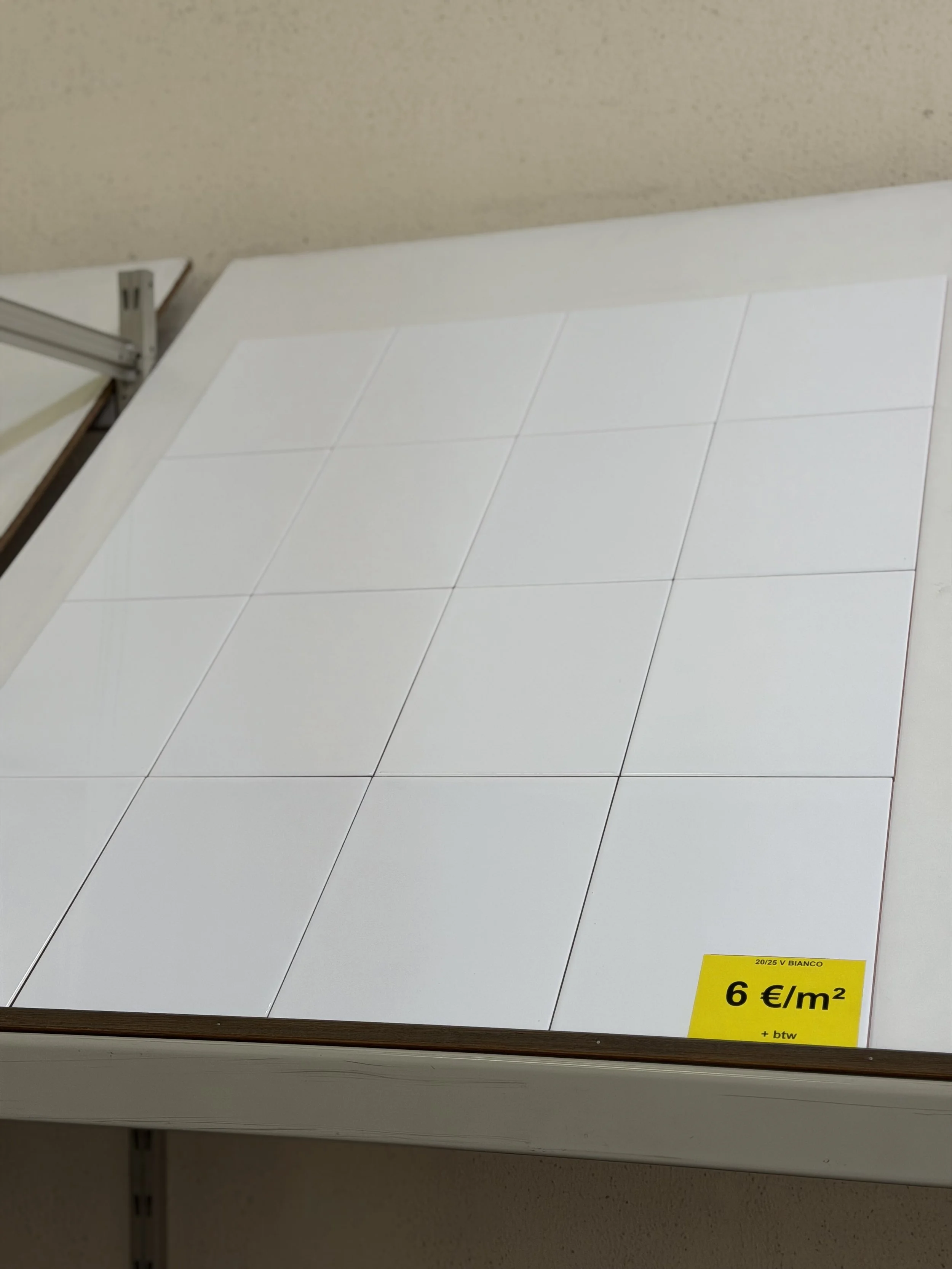 Witte keramische vloer- of wandtegels op display met een prijskaartje van 6 euro per vierkante meter.
