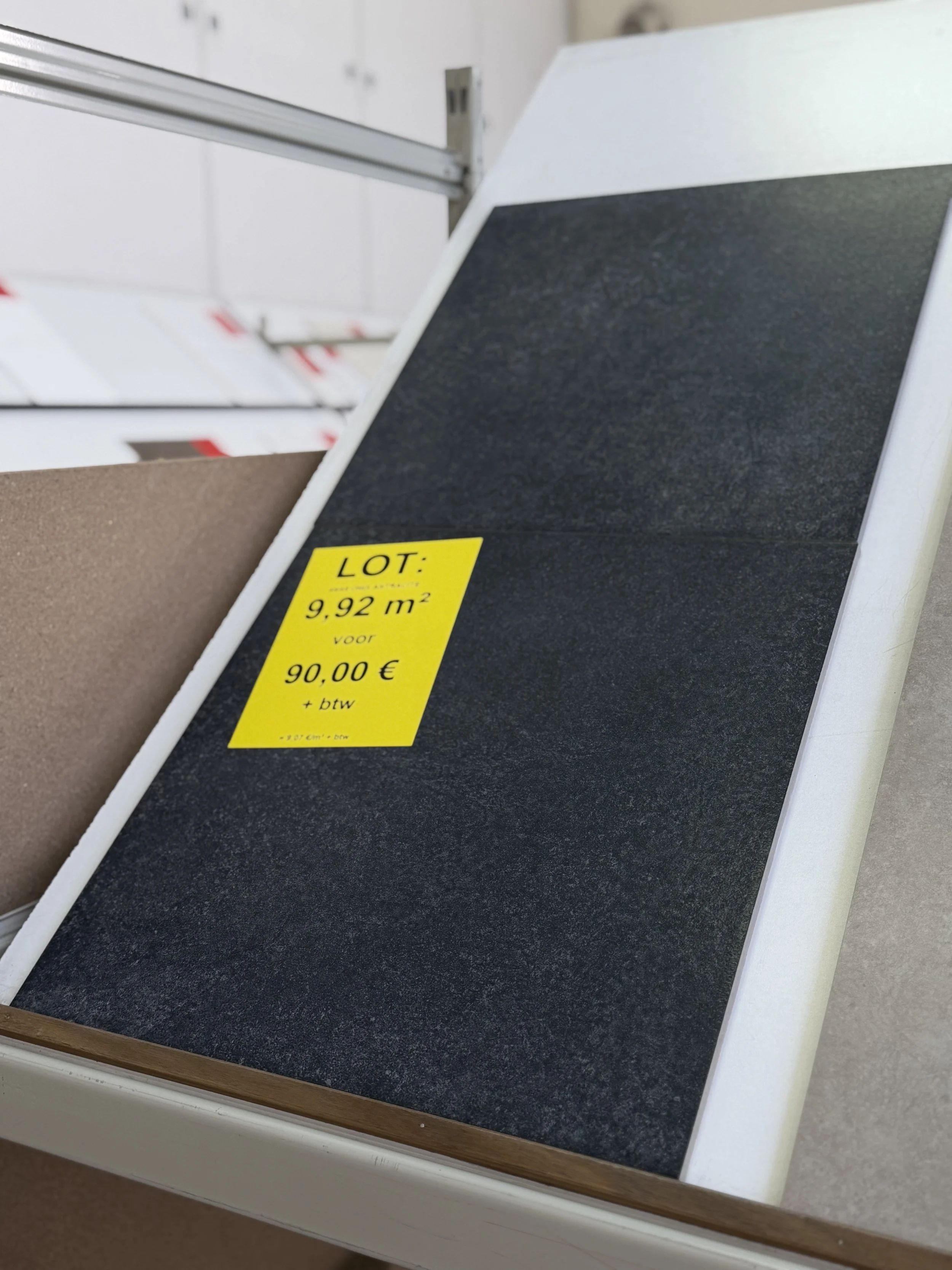 Verschillende steensoorten en materialen op display in een winkel, met een geel prijsbord dat 9,92 m² en 90,00 € vermeldt.