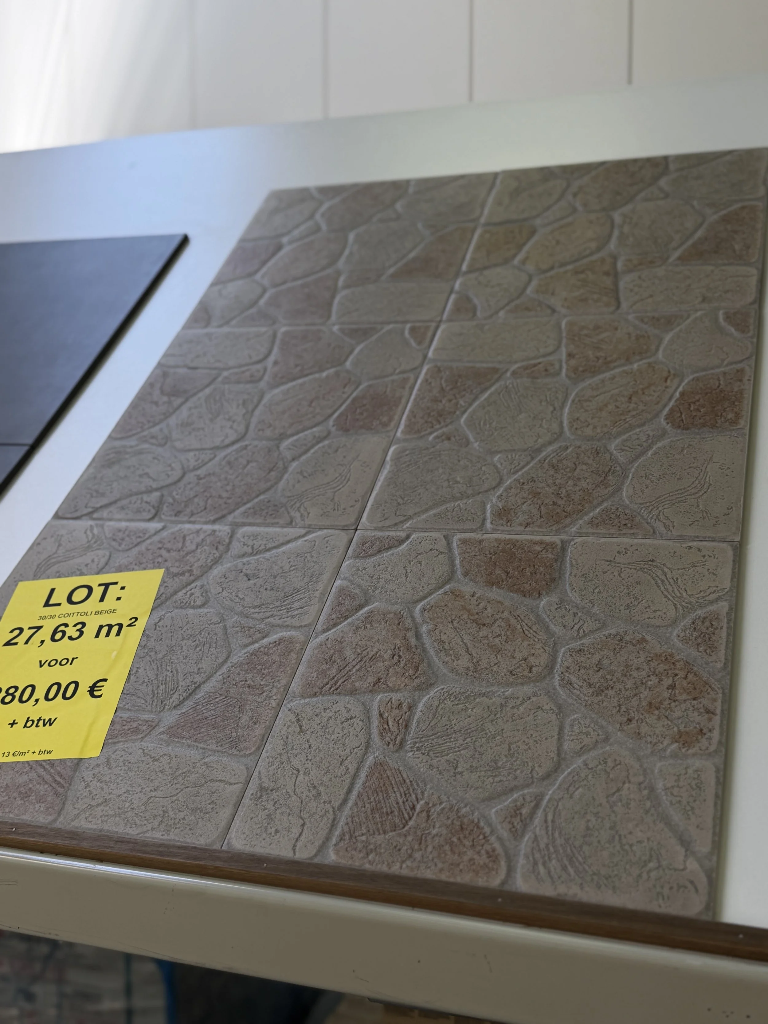 Tegelmet op een display met een prijslabel voor beige stenen tegels, oppervlakte 27,63 m², prijs 880 euro