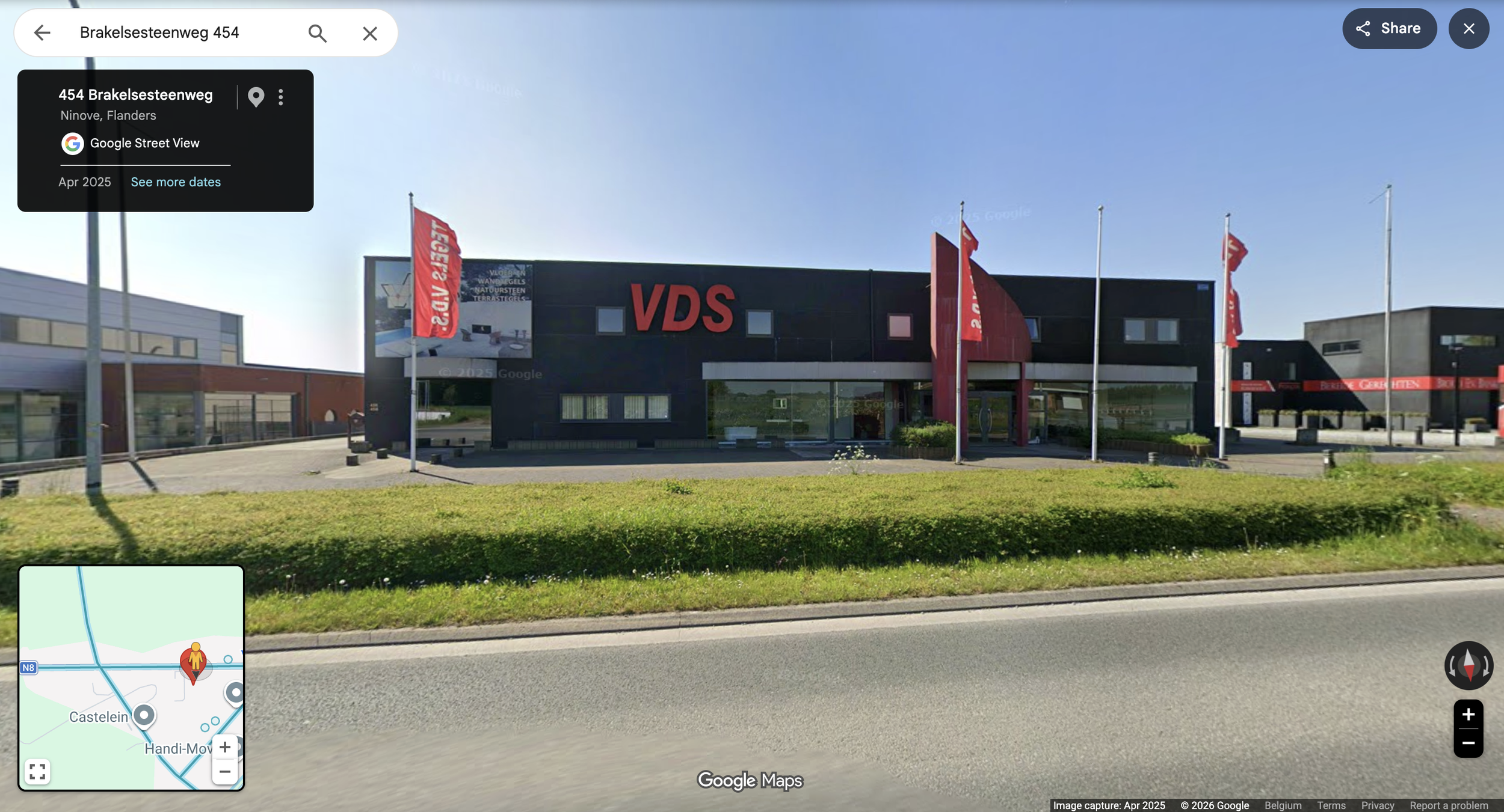 Een modern zwart gebouw met grote rode letters 'VDS' op de voorgevel, vlaggen met Bedrijvenreclame en een reclamebord. De locatie is Brakelse Steenweg 454 in Ninove, Vlaanderen, België.