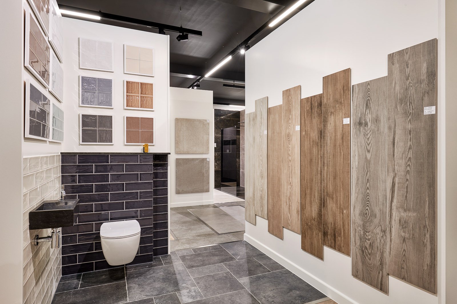 Binnenruimte van een showroom met kleurrijke tegels en houten meubels, inclusief een wc en een wastafel.