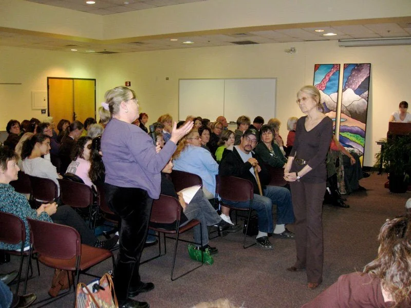 Woman standing at an event to ask Gloria Steinem a question
