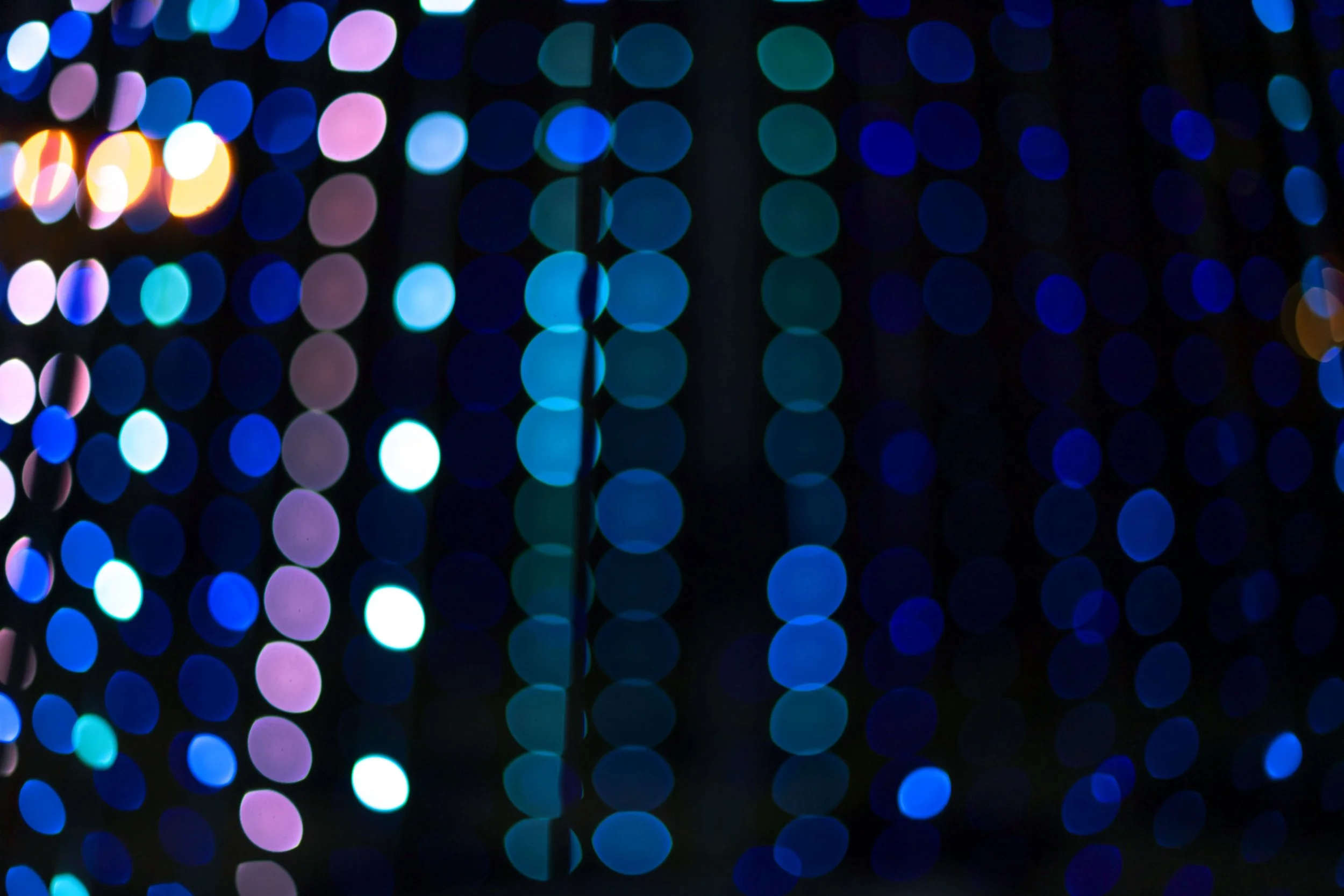 Blue bokeh lights that look like sequins on a black background