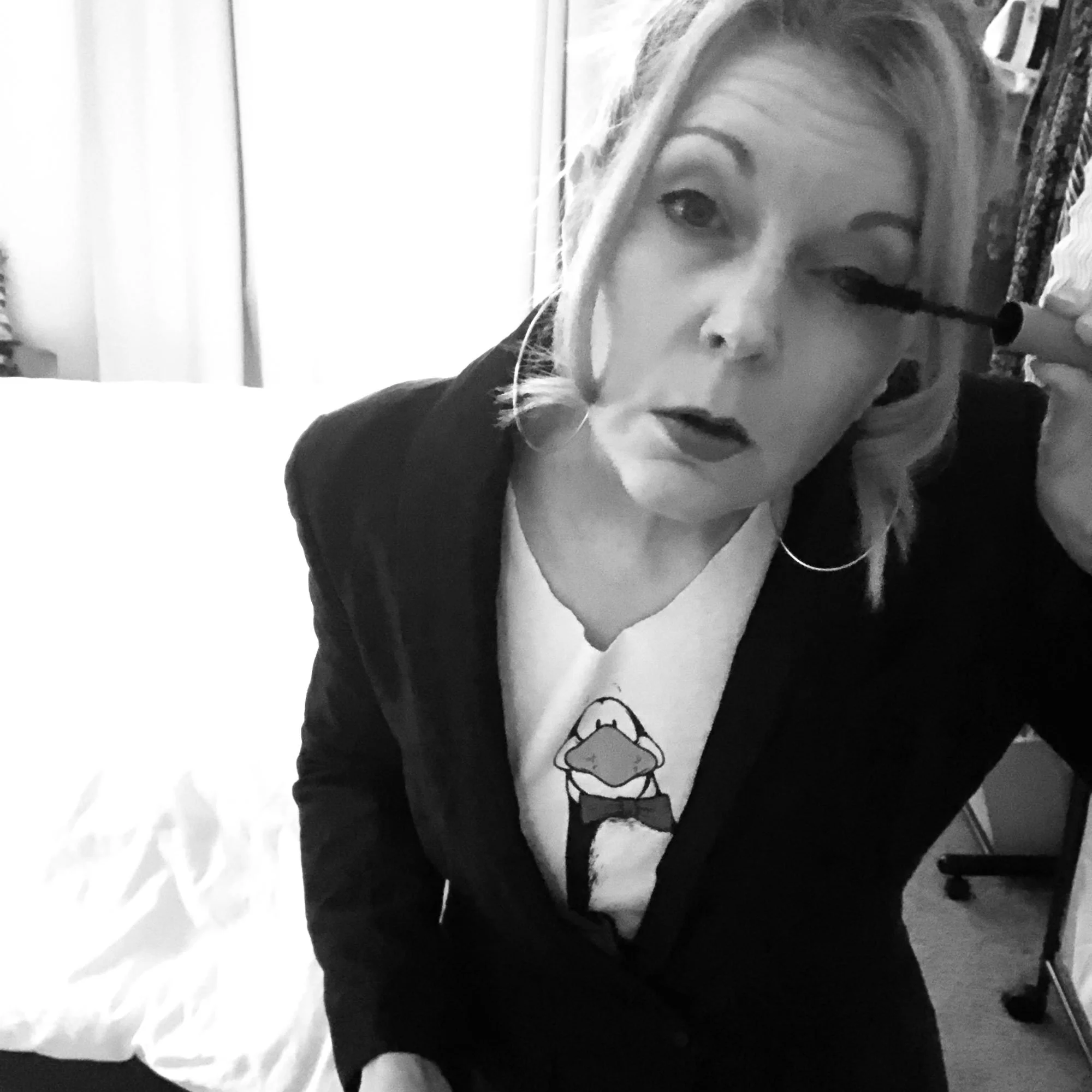 Claudette Silver wearing a black blazer while applying mascara