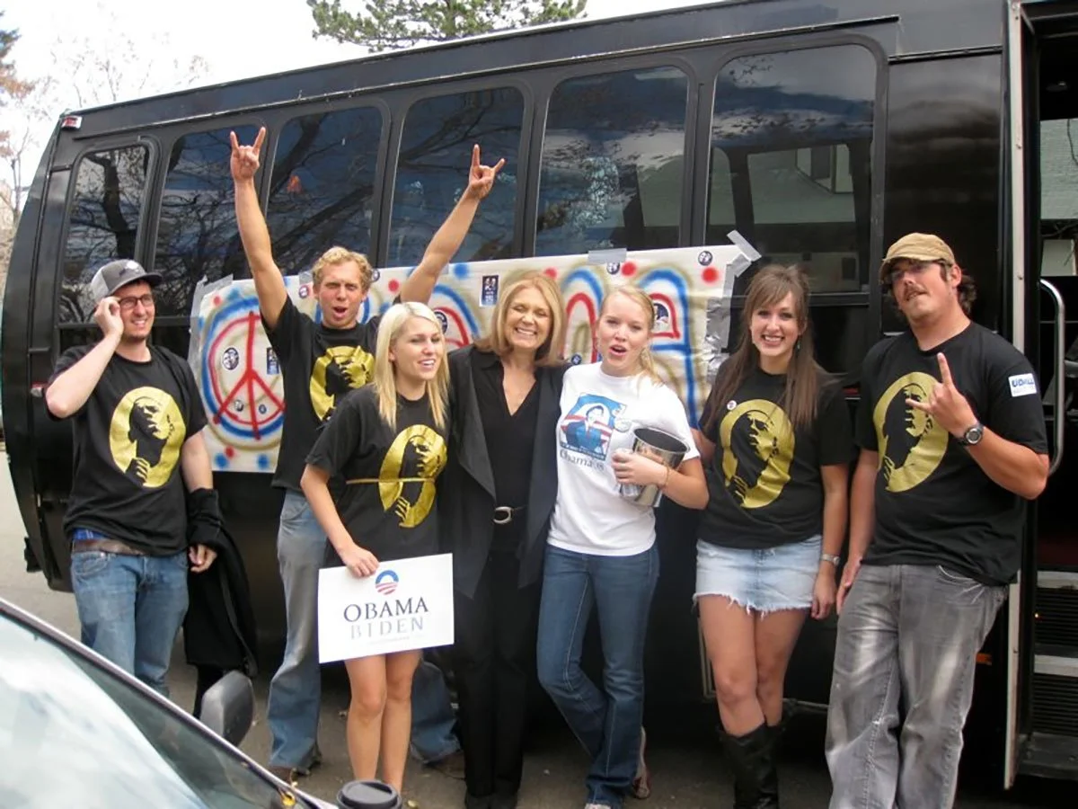 Group of women standing in front of a tour bus with Gloria Steinem