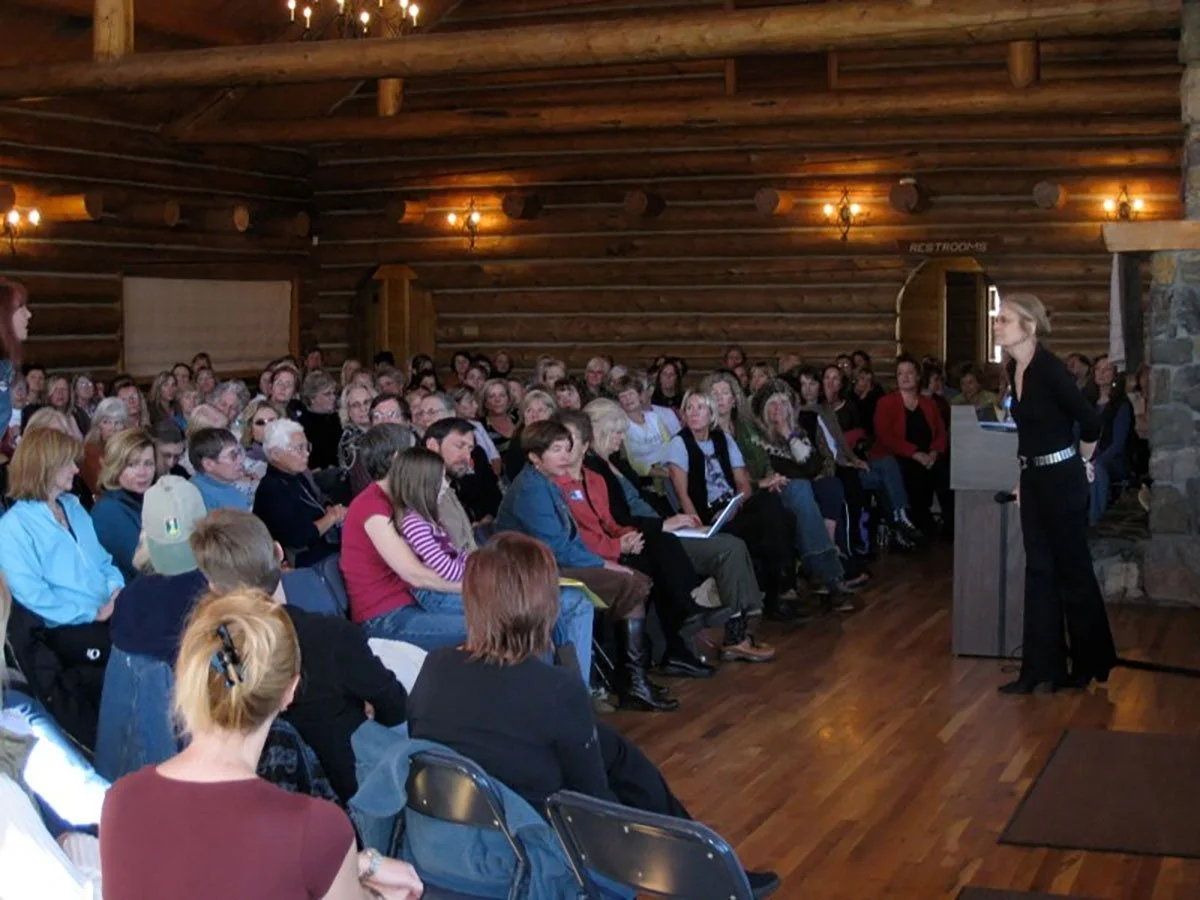 Large crowd sitting in chairs in front of Gloria Steinem at a podium