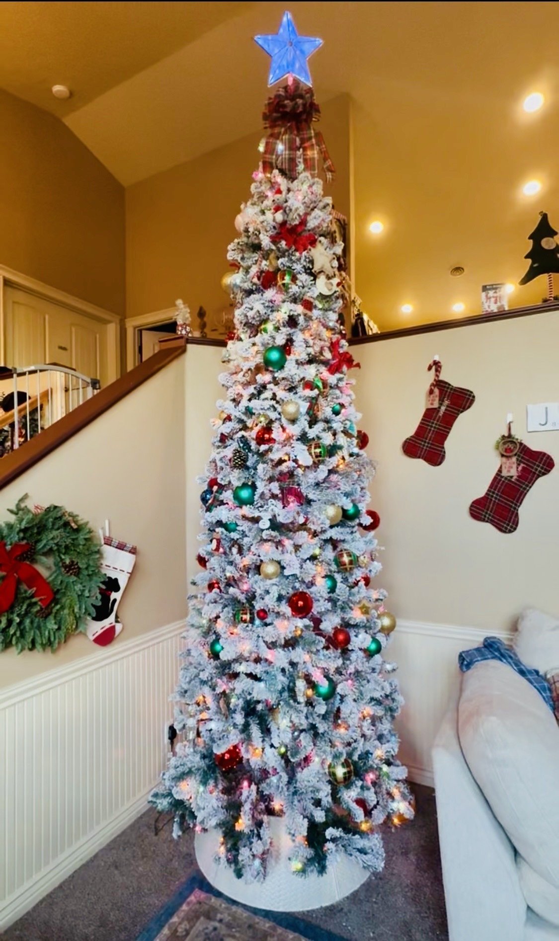 Bespoke Interior Holiday Lounge- A towering, expertly styled flocked tree paired with a custom, artist-crafted interlocking family tile presentation on Cherry Tree Lane.. 
