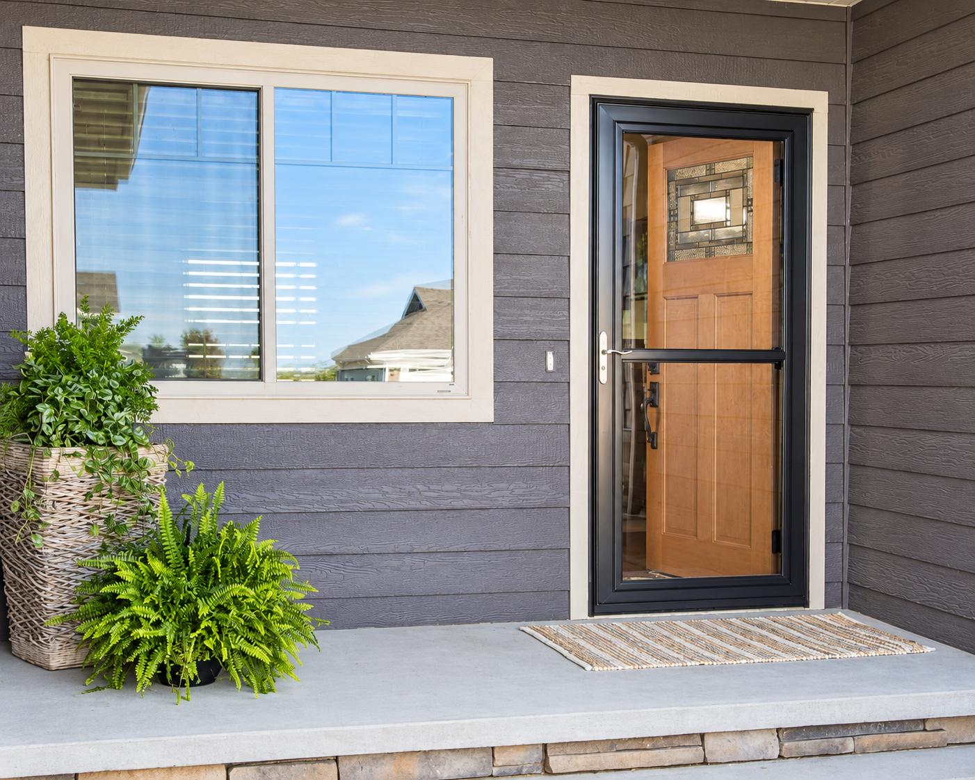 Front porch with a window, door, potted plants, and a striped doormat.