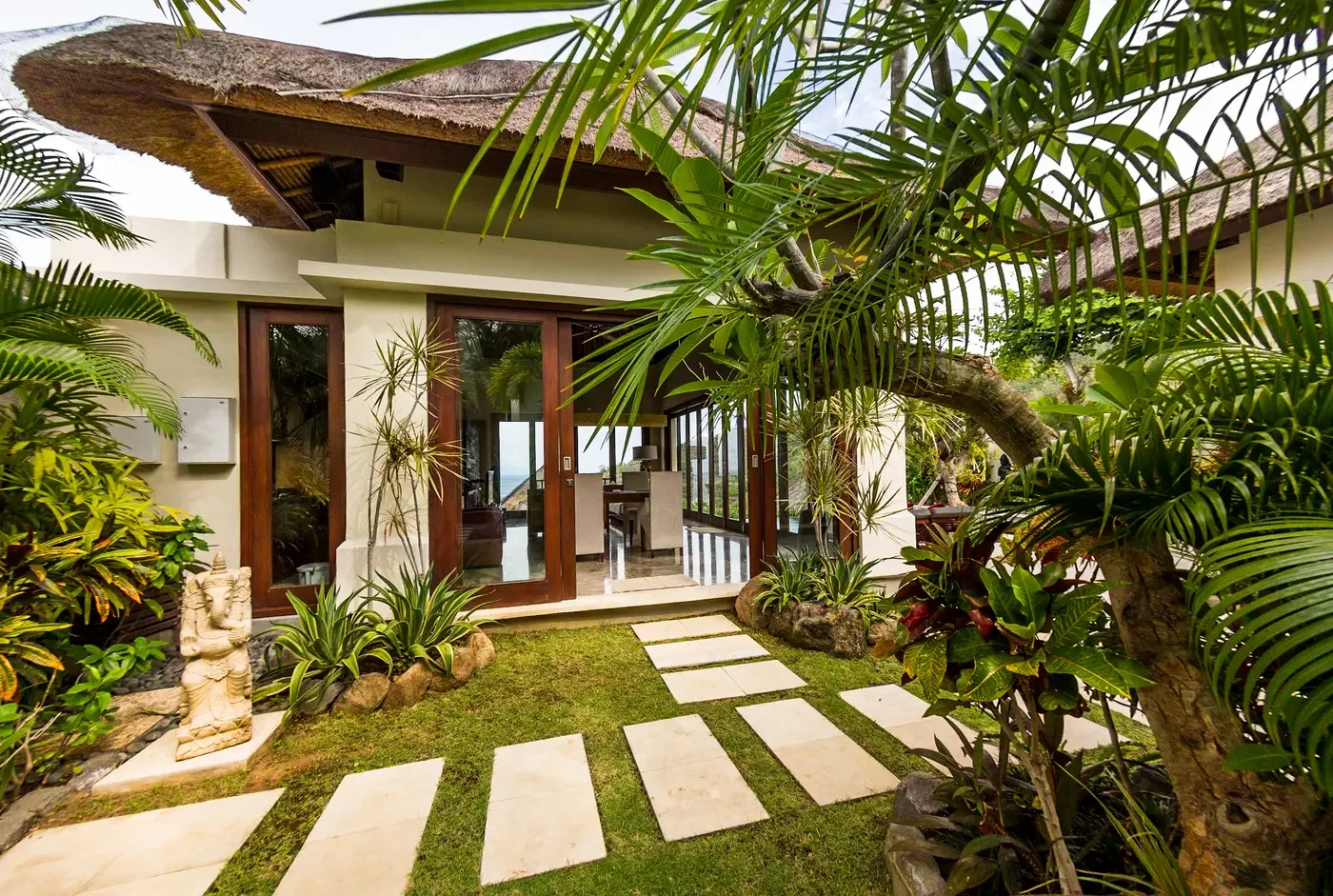 Private villa entrance with a landscaped garden pathway and glass architectural doors.