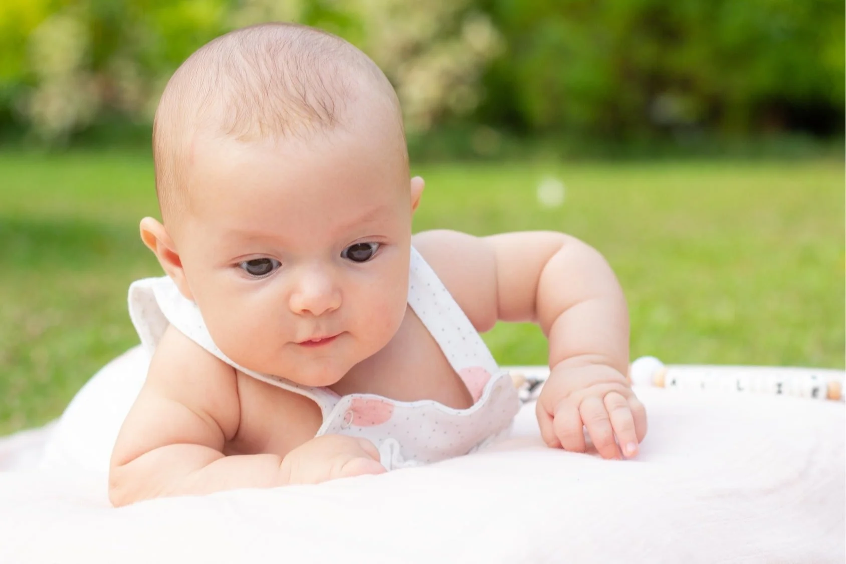 Curious baby on a soft blanket in the garden, gentle natural light baby photography