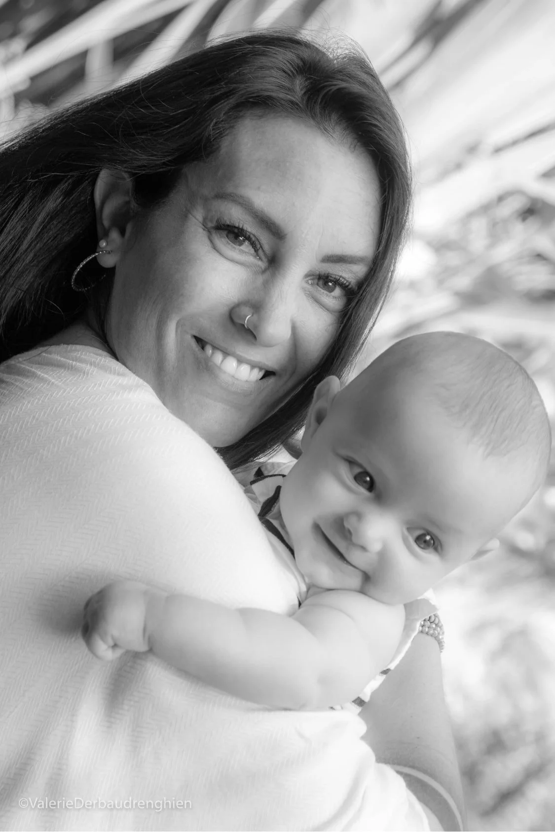 Smiling mother holds her baby over her shoulder, a black and white mother and baby portrait