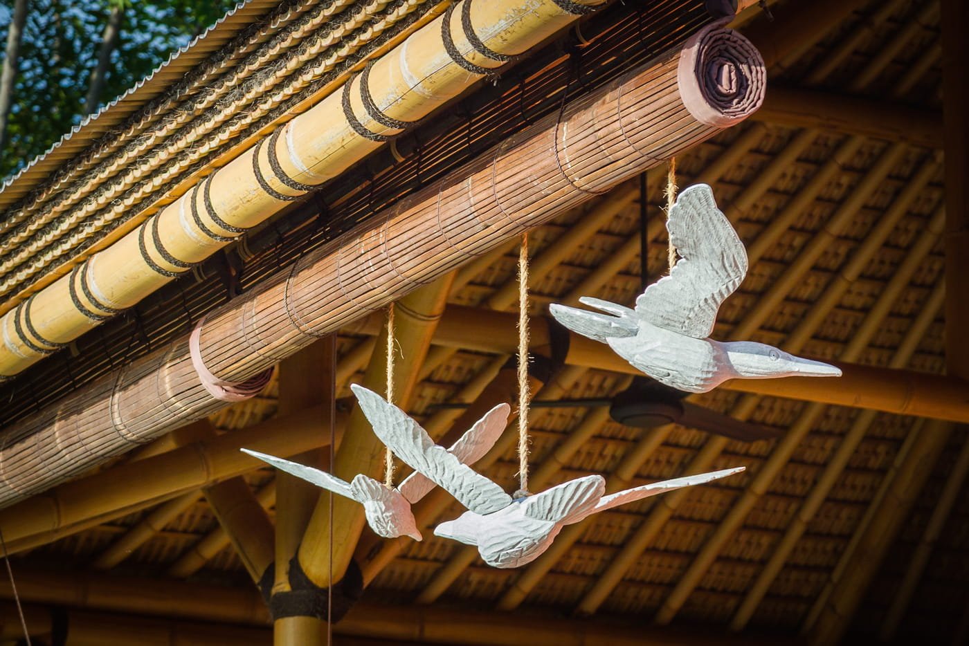 Close-up of hand-carved white wooden birds suspended from a bamboo roof structure at Aquamarine Beach Villas in Amed, Bali, photographed by Seña Studio.