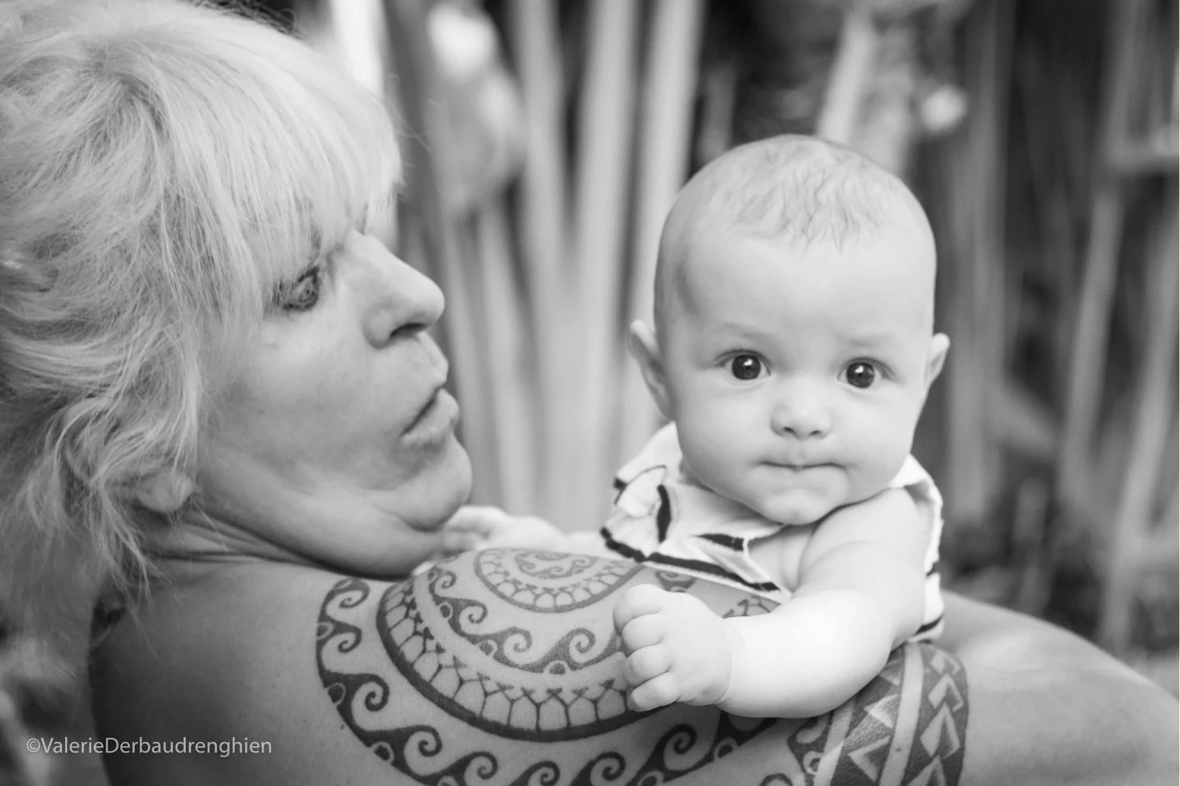 Baby looks over grandmother’s shoulder, a black and white grandparent and grandchild portrait