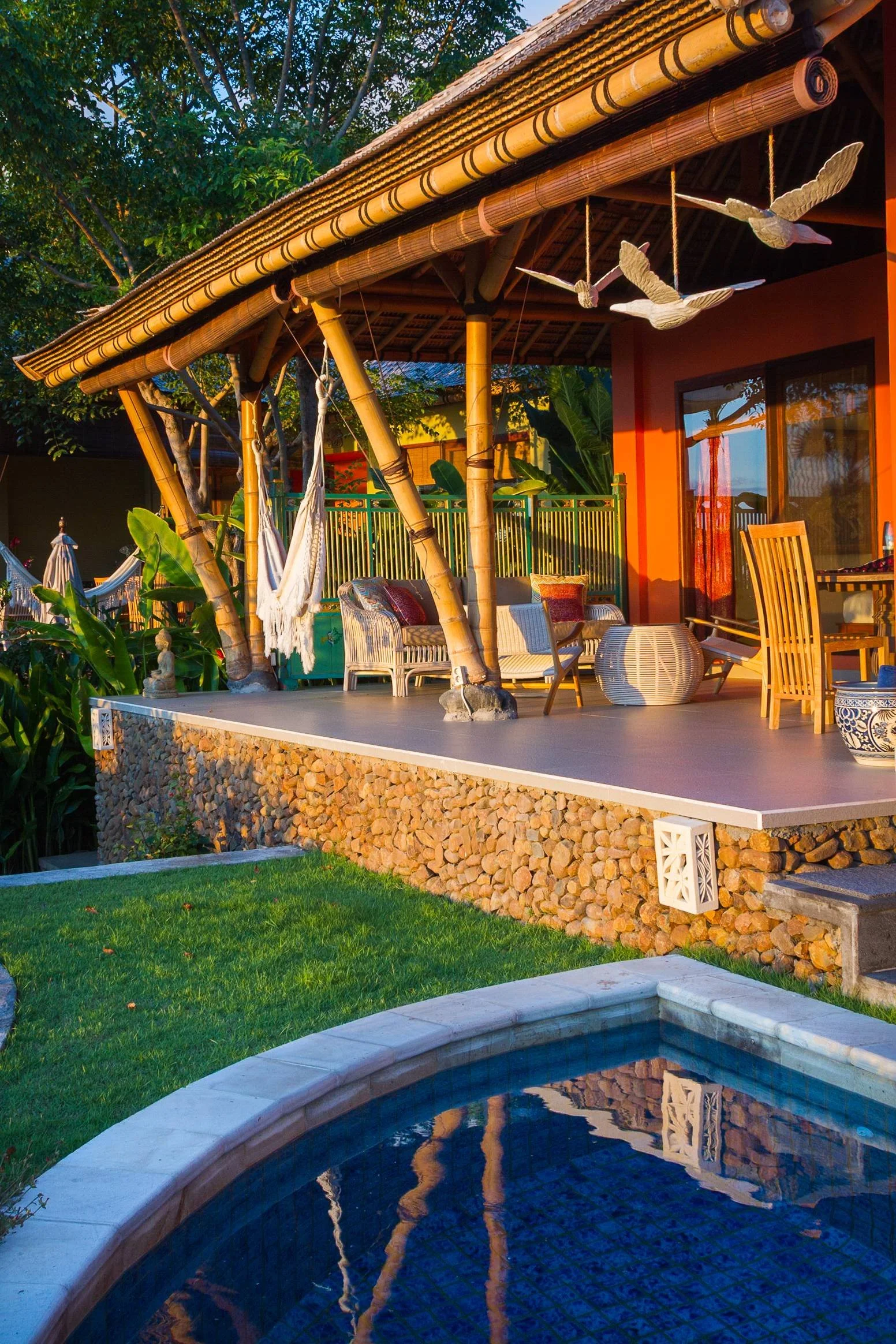 Warm golden-hour shot of a stone-built bamboo veranda with a hanging hammock and seating area next to a private plunge pool at Aquamarine Beach Villas in Amed, Bali, photographed by Seña Studio.