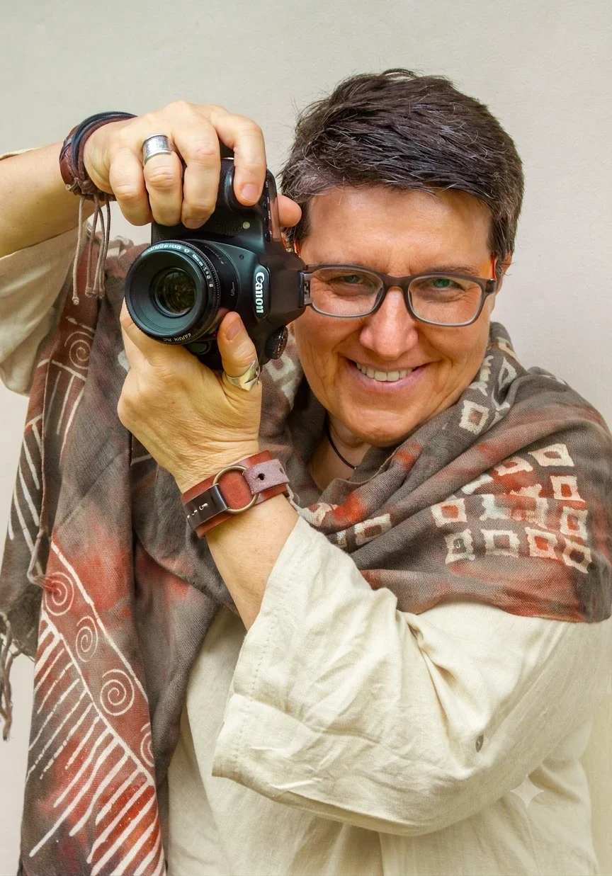 Valérie Derbaudrenghien smiling behind her Canon camera, founder and lead photographer at Seña Studio specializing in hospitality and architectural photography.