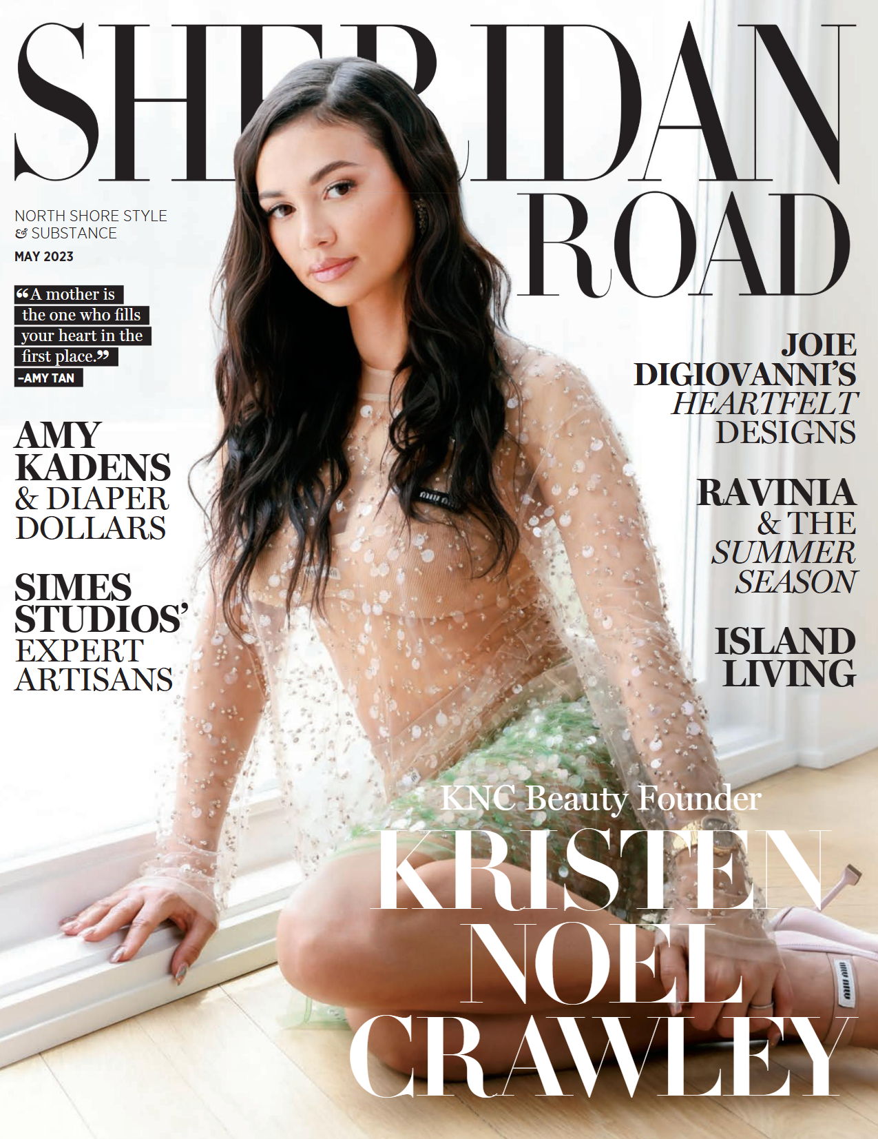 Magazine cover featuring Kristen Noel Crawley, who has long dark hair and is wearing a sheer, embellished top, sitting on the floor by a window with a soft smile.