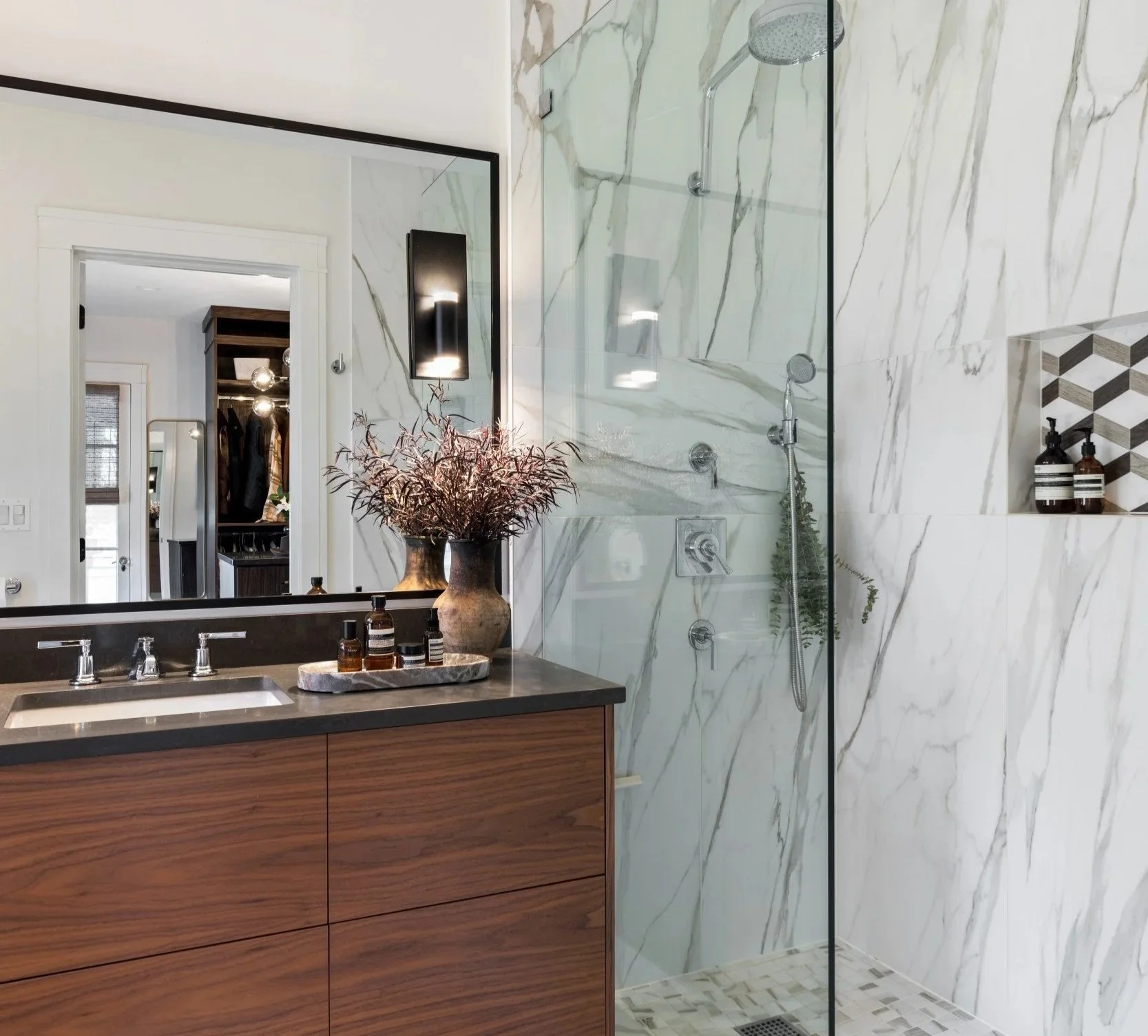 Modern bathroom with a wood vanity, marble shower walls, and a walk-in shower with glass partition.