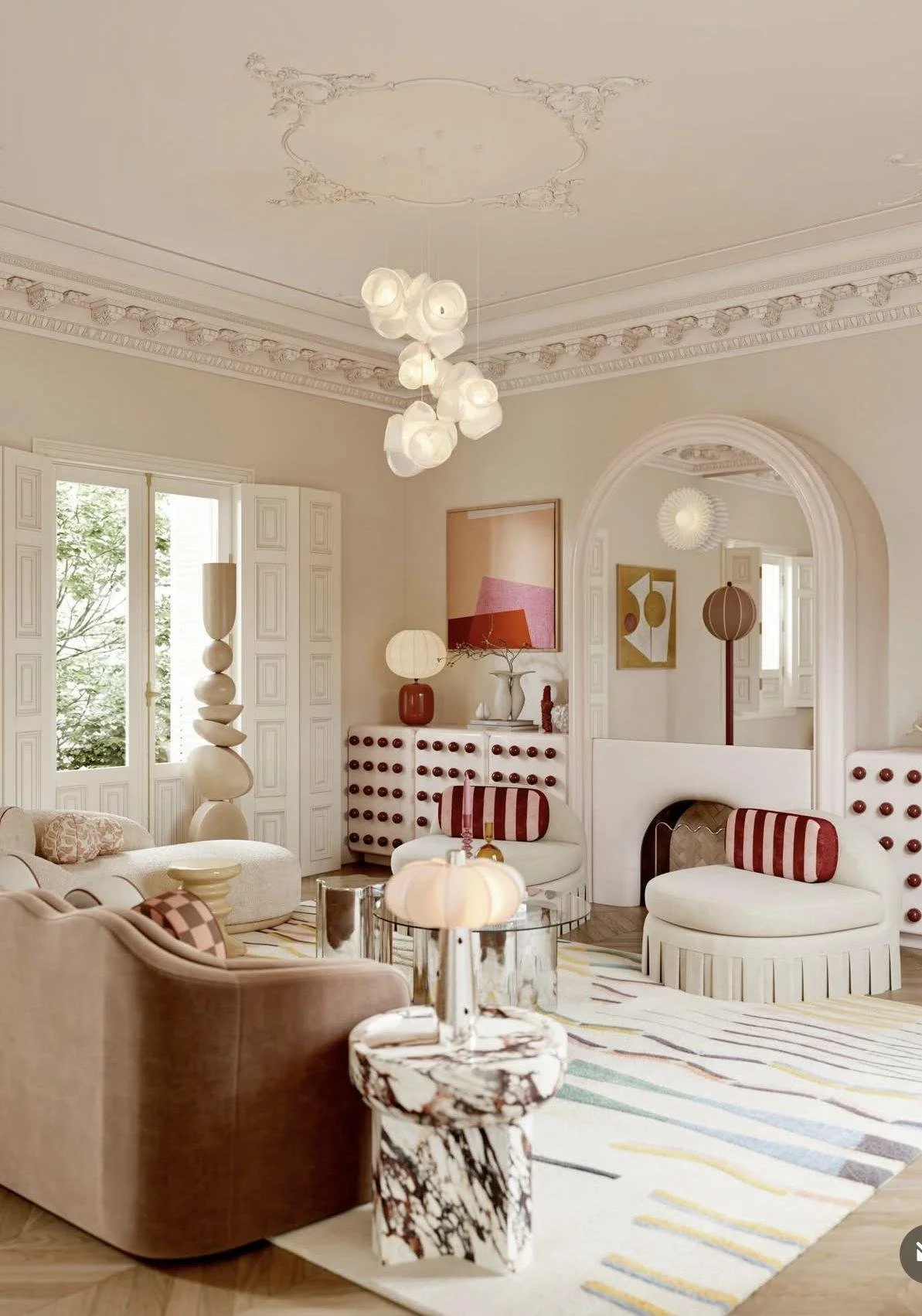 Collected living room pairing ornate architectural moldings with sculptural lighting, distinctive furniture, expressive artwork, and playful red accents.