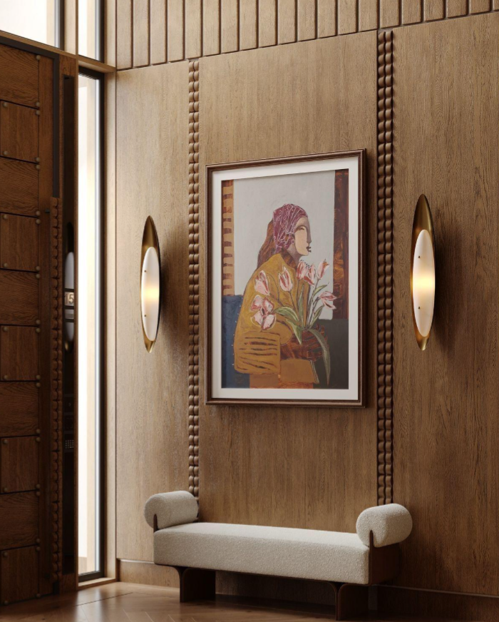 Custom wood-paneled entryway with carved detailing, integrated wall sconces, framed artwork, and a sculptural upholstered bench.