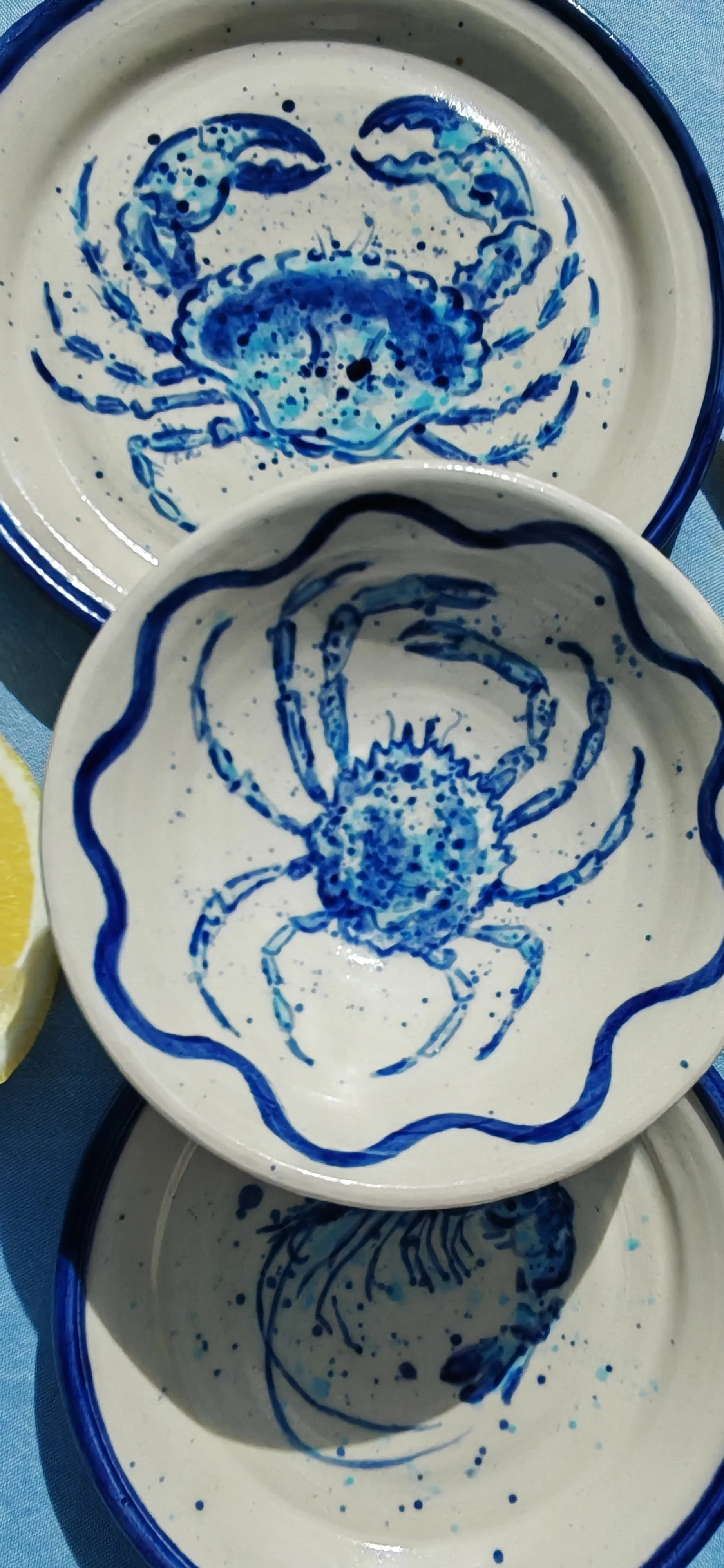 Ceramic dishes with blue crab illustrations painted on the inside surface.