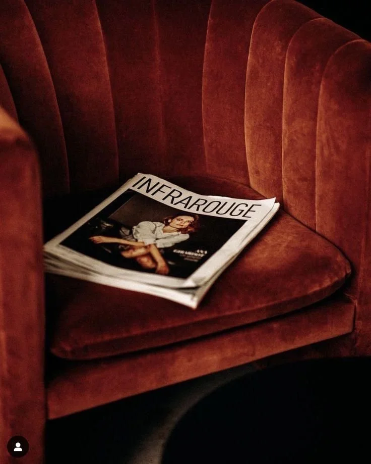 Un magazine intitulé 'INFRAROUGE' posé sur un fauteuil en velours rouge.