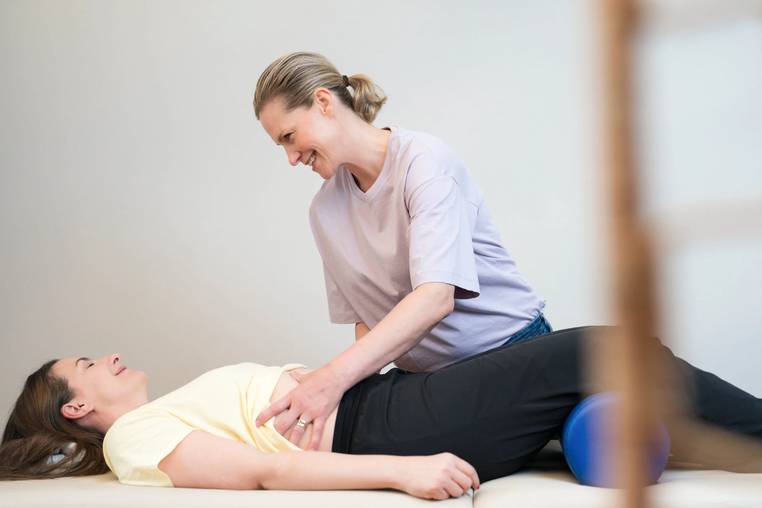 Physiotherapeutin Christina Frisch tastet sanft die Bauch- und Beckenbodenmuskulatur einer Patientin auf der Behandlungsliege ab