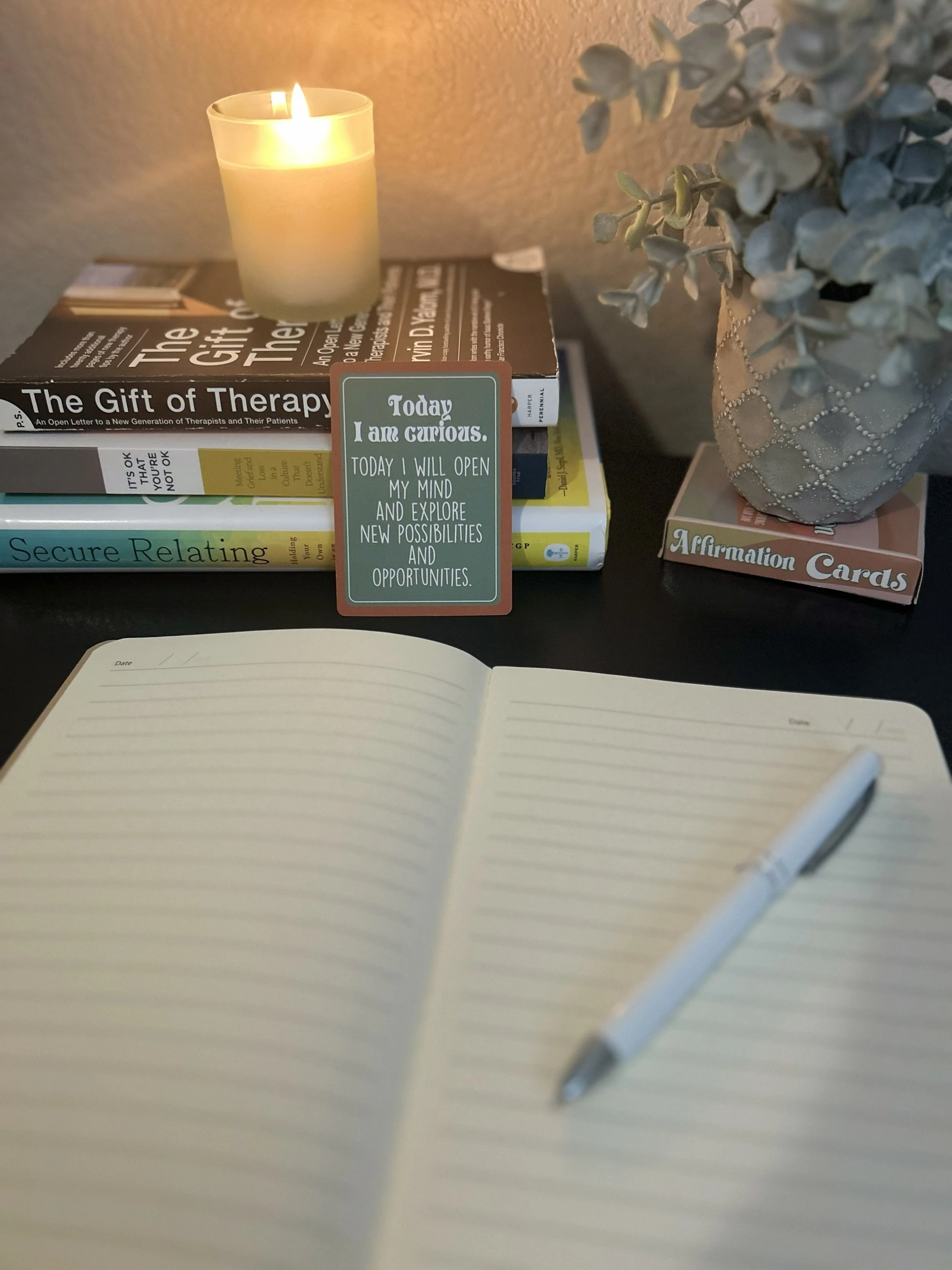 Open journal next to a stack of books with an affirmation card that reads: Today I am curious.