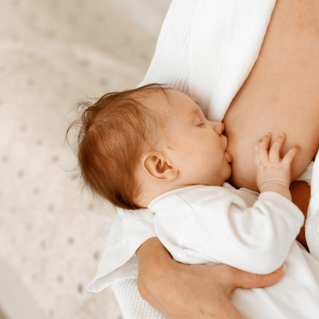 A newborn baby breastfeeding at mother's breast in a close-up shot.