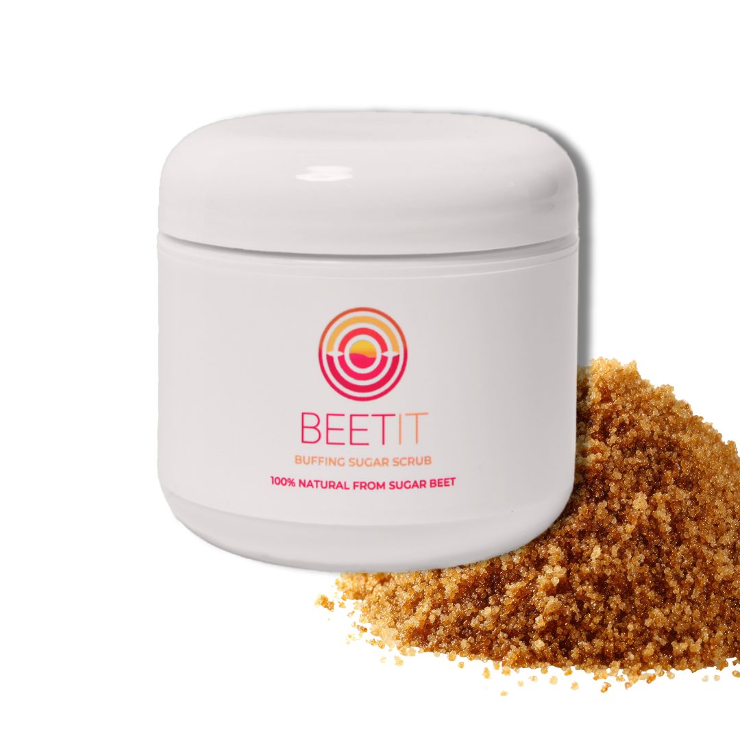 A white jar labeled 'BEETIT Buffing Sugar Scrub' with pink and yellow circular logo and text '100% natural from sugar beet'. Next to the jar is a pile of brown sugar scrub.