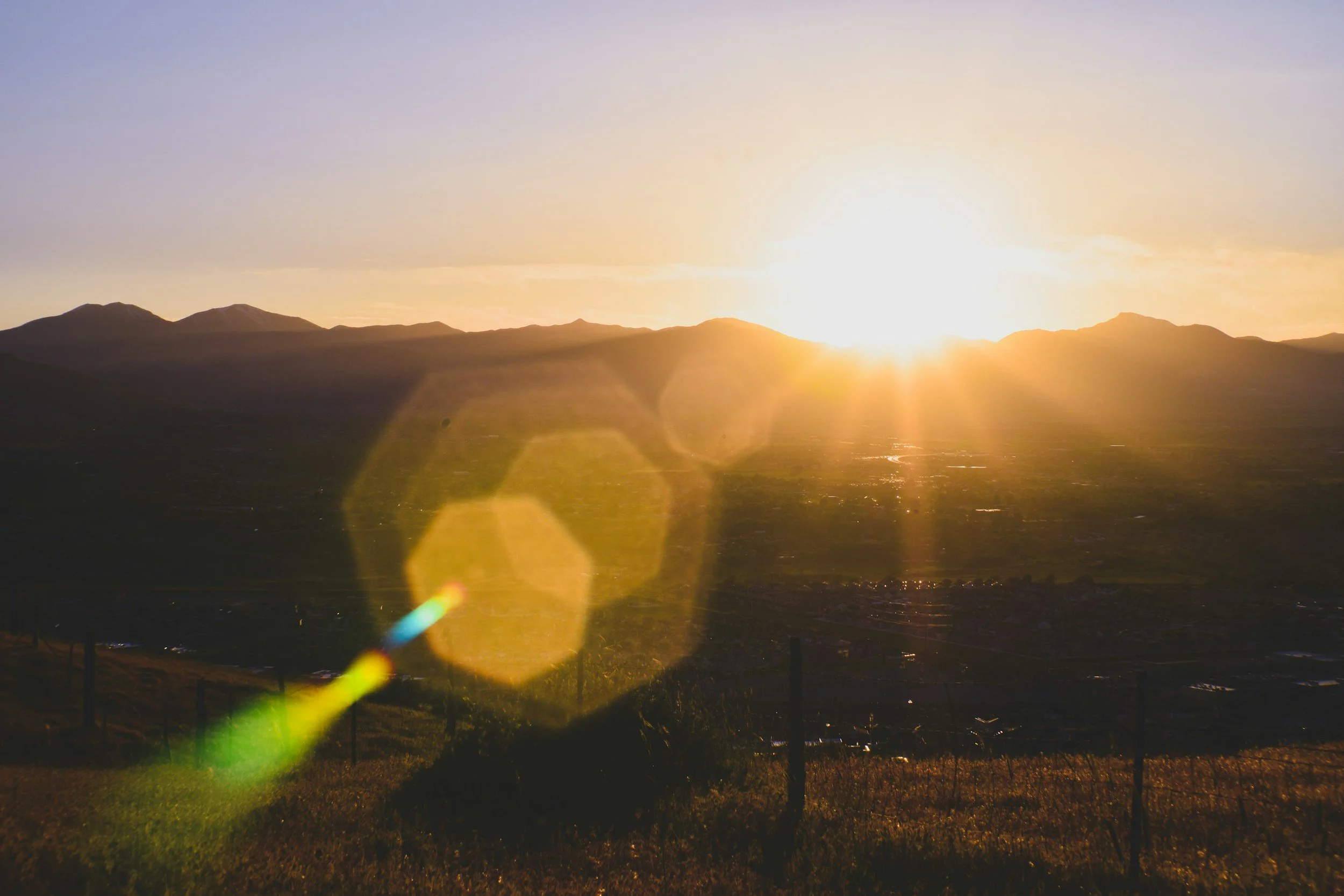 Coucher de soleil sur des montagnes avec un ciel dégagé et un reflet de lumière dorée sur la vallée.