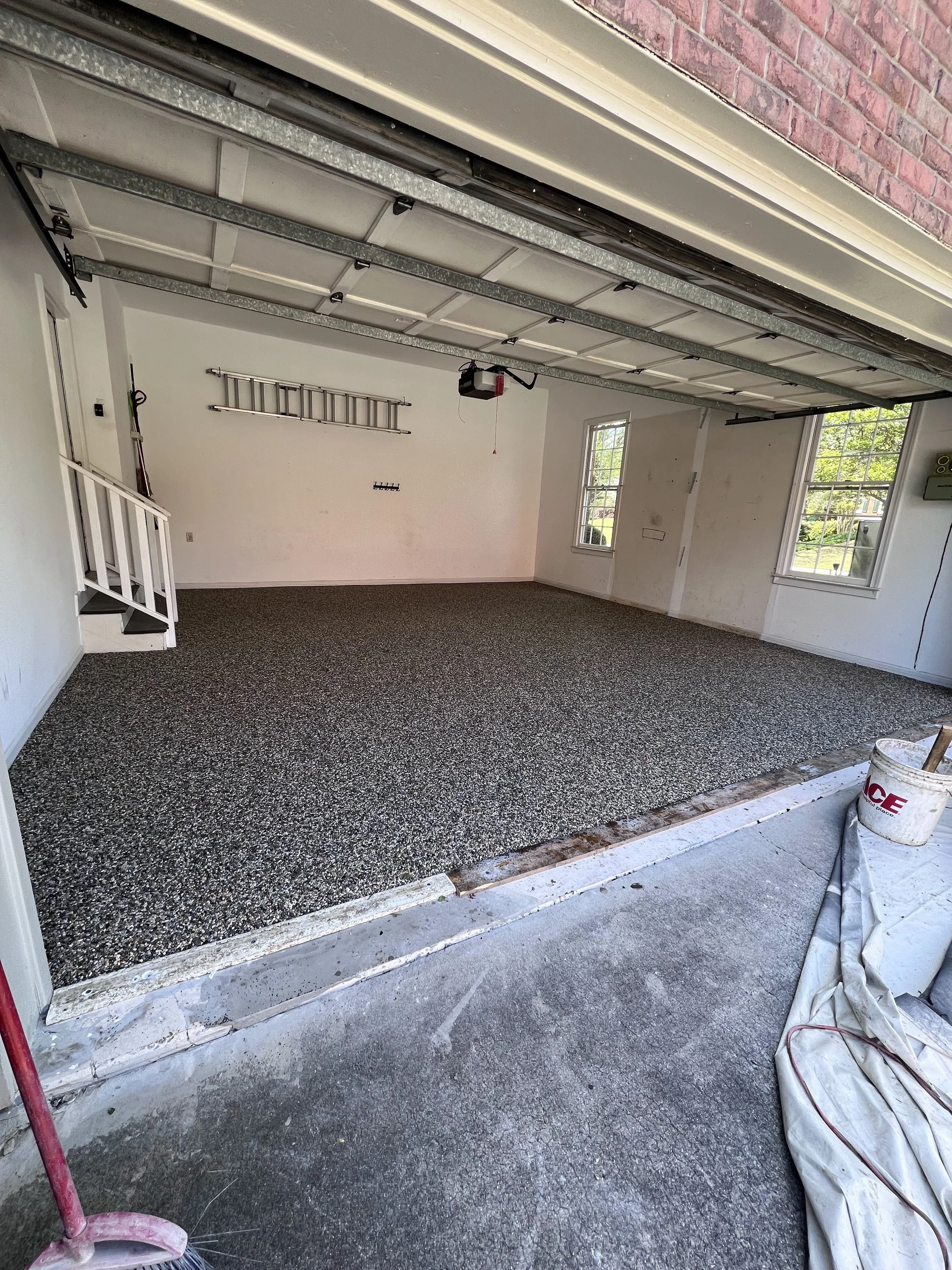 Garage with new resin-bound pebble flooring designed and installed by Pebble & Resin Co, with tools and supplies around.
