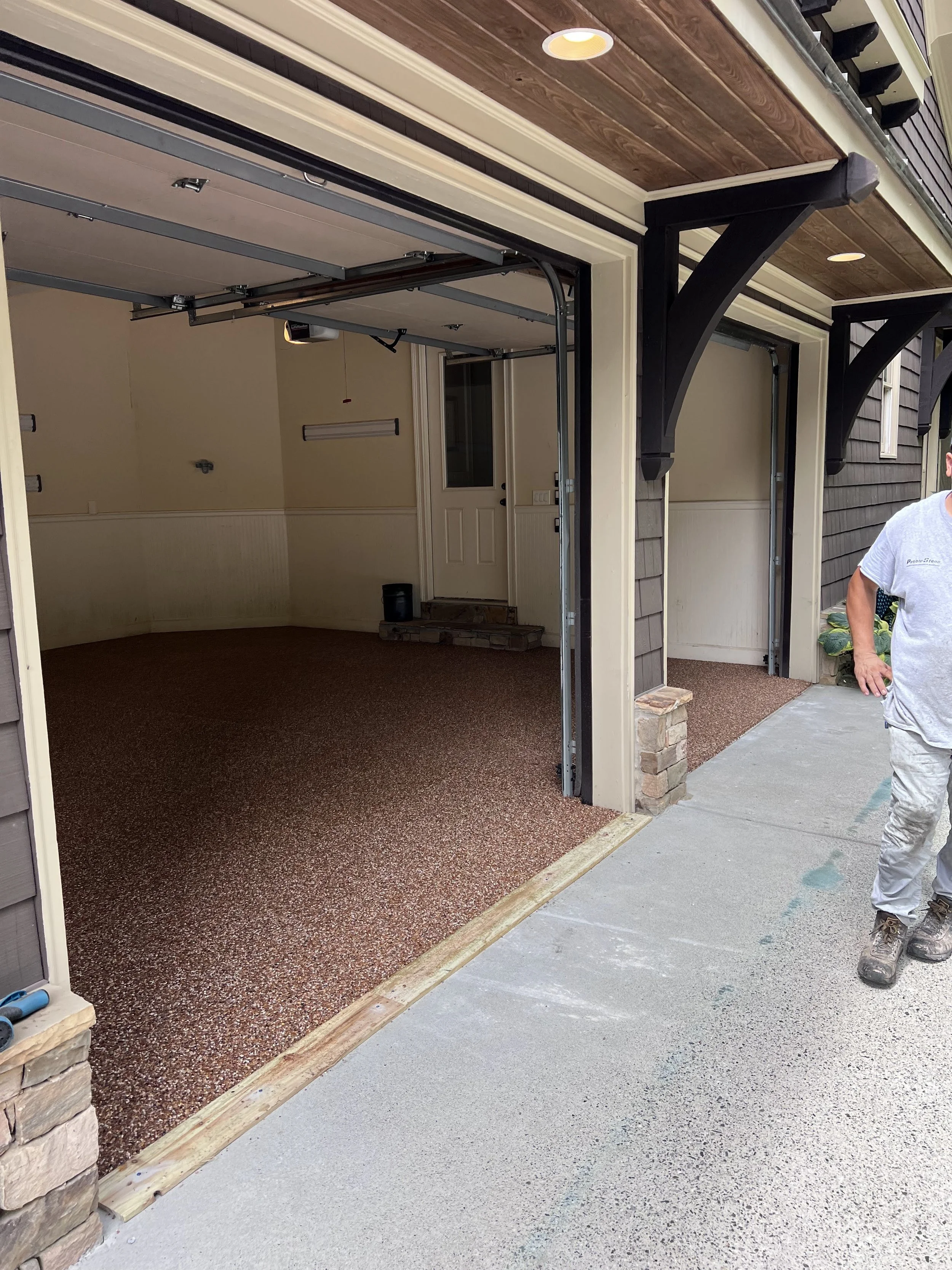 The image shows the interior of a garage with resin-bound pebble flooring designed and installed by Pebble & Resin Co.