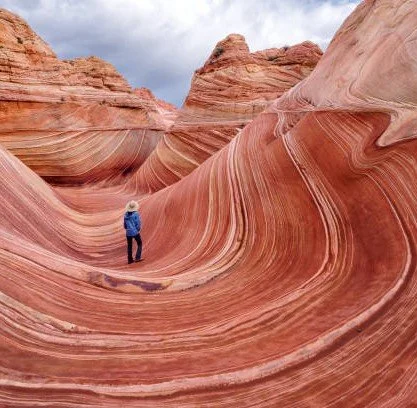 Person standing on colorful, layered rock formations in a desert landscape