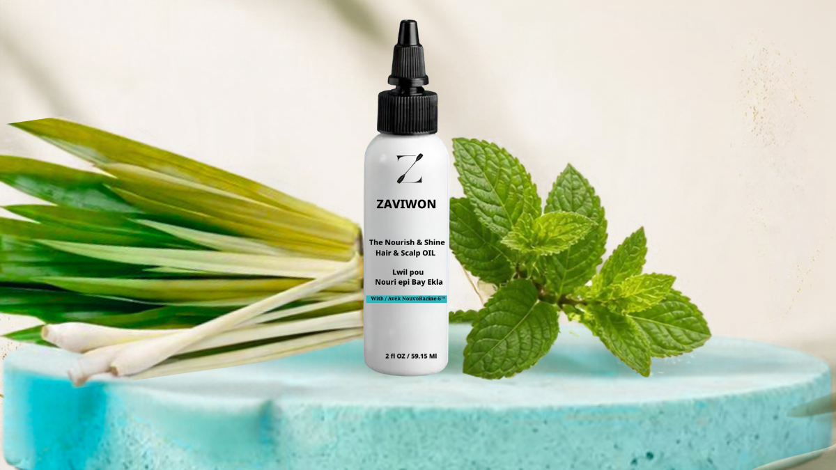 Our scent. A bottle of Zaviwon hair and scalp oil placed on a blue surface, with fresh green lemongrass stalks and mint leaves behind it.