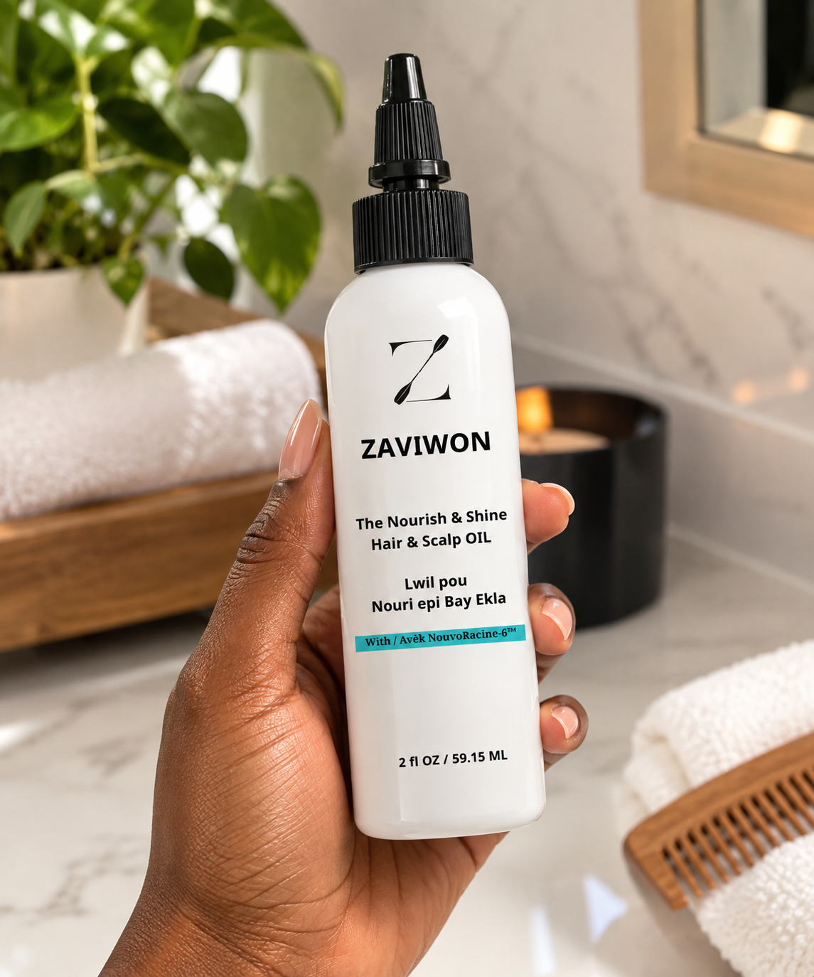 Hand holding a white bottle of Zaviwon hair and scalp oil with black pump cap in a bathroom setting with plants and towels in the background.