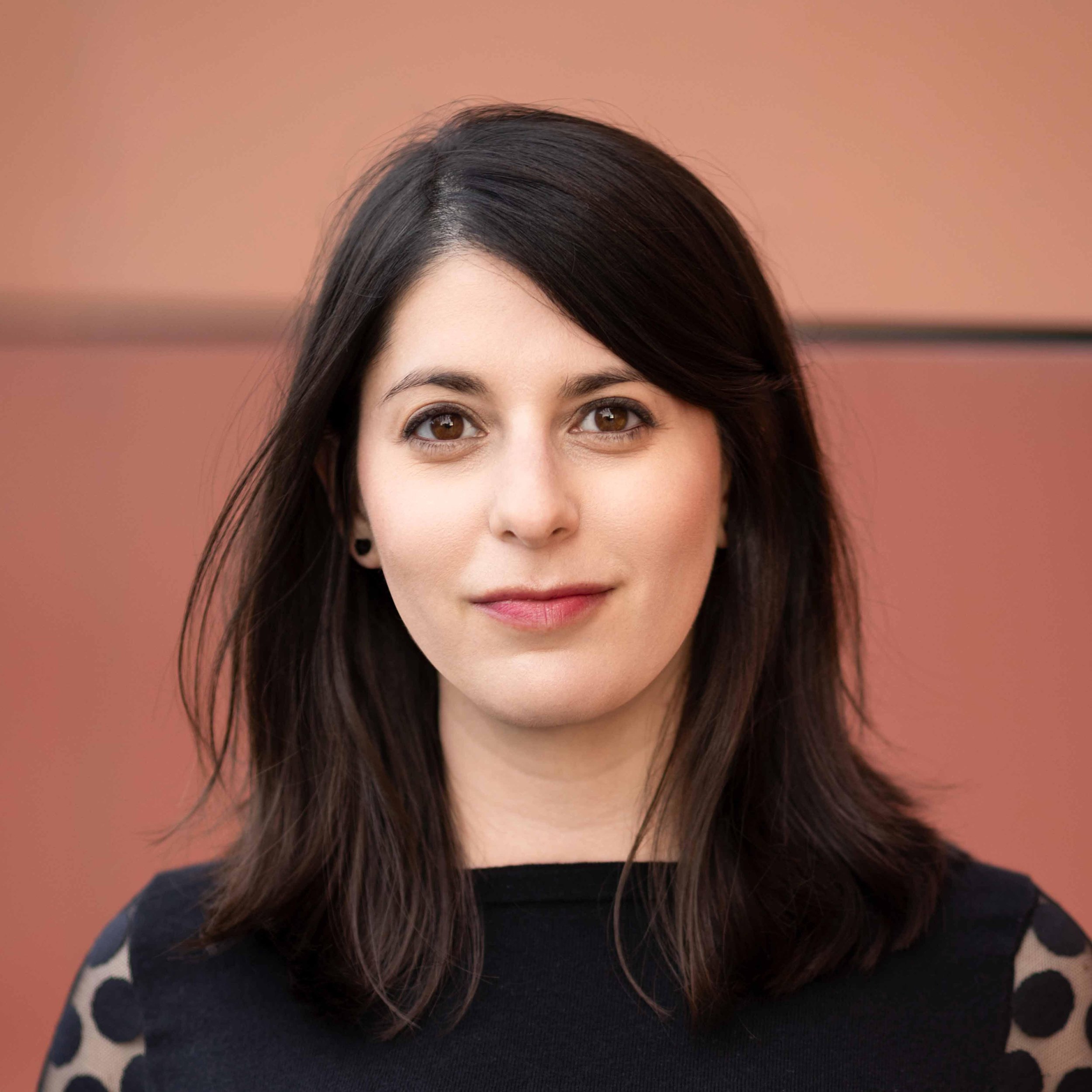Headshot of Emily Greenberg against a muted pink background.