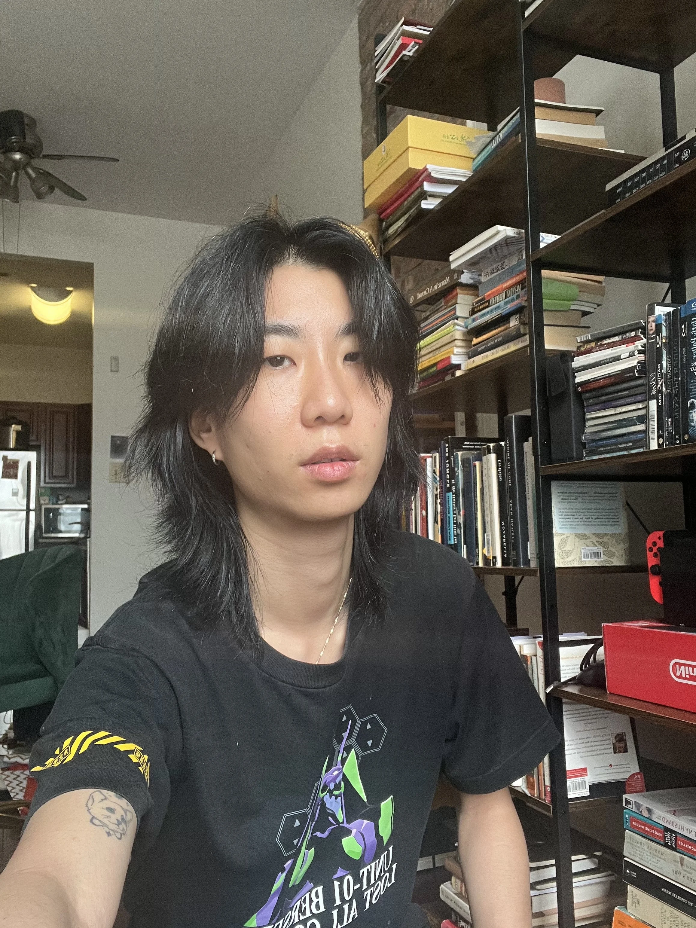 Headshot of jonah wu sitting in front of a bookshelf filled with books.