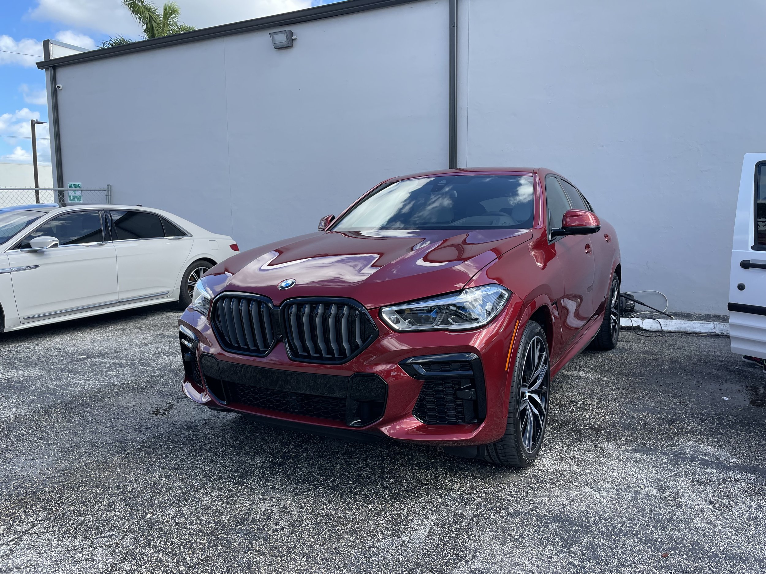Glossy maroon BMW X6 SUV after complete paint enhancement and exterior detail by LOVAN'S in Royal Palm Beach, FL.⁠