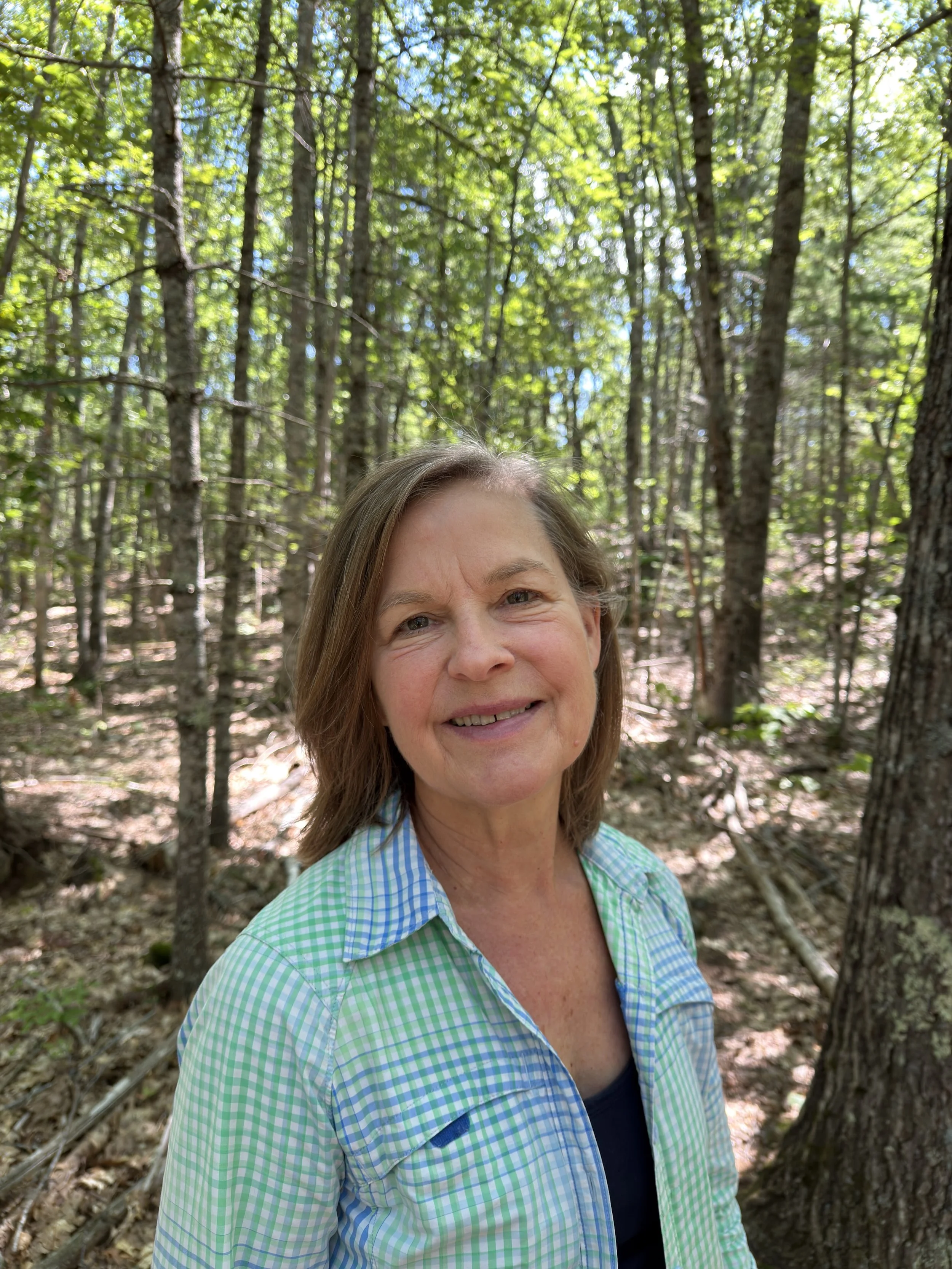 woman with brown hair smiling in the woods of Maine