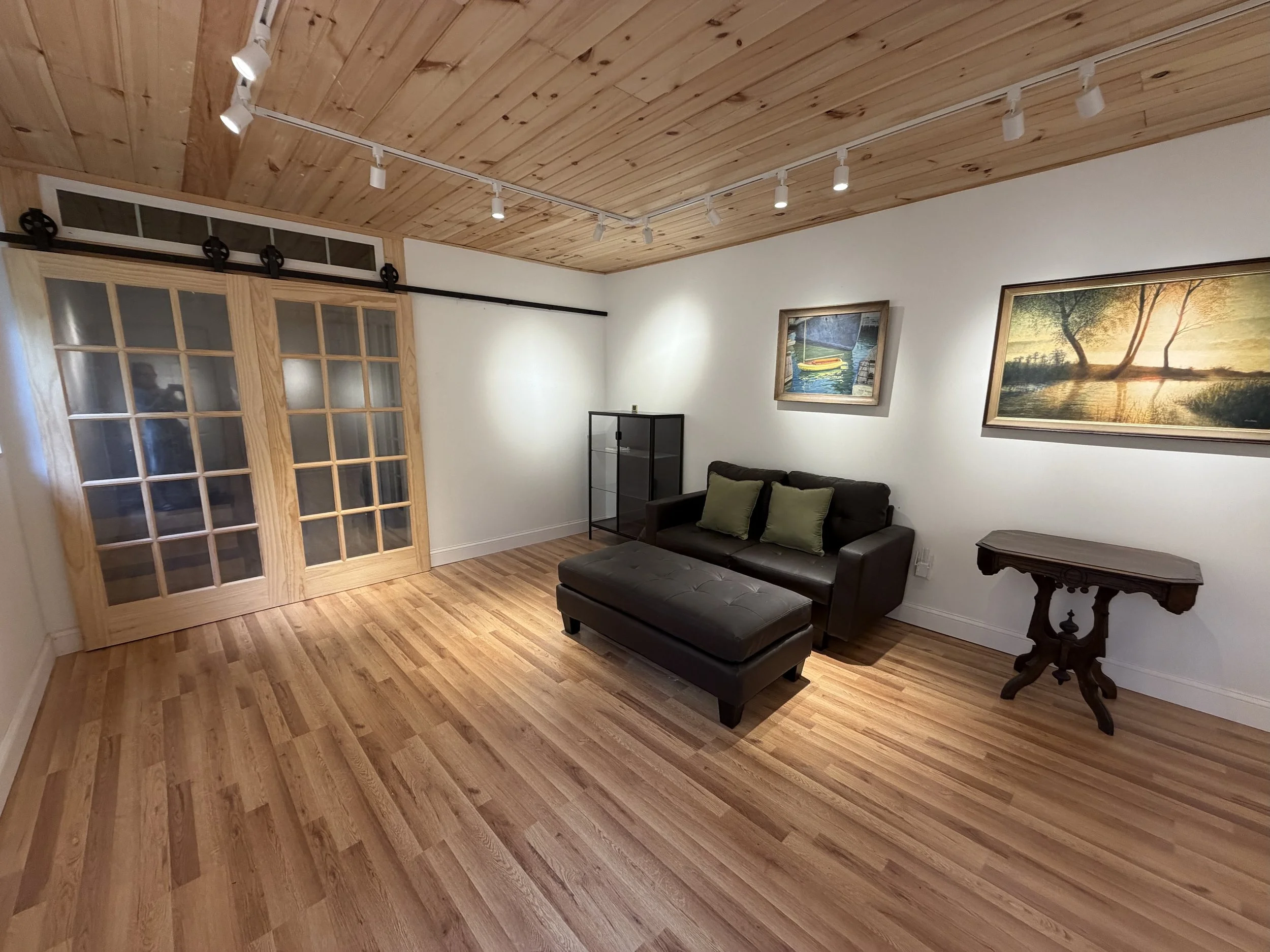 Interior of remodeled barn studio with paintings of nature on the walls and wooden floors and ceiling